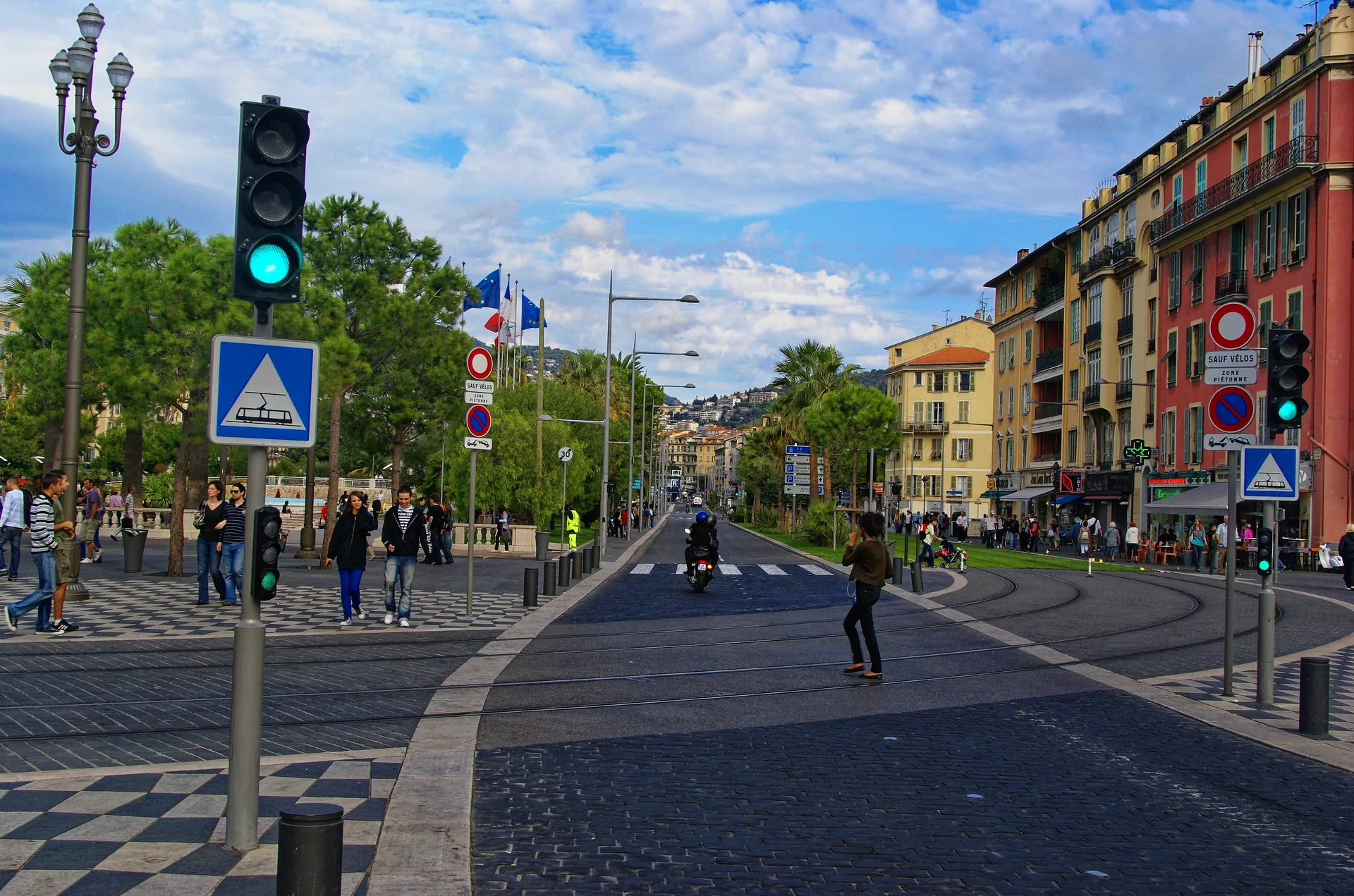 Place Masséna em Nice, com pavimento geométrico, trilhos do tram, edifícios e pedestres ao fundo.