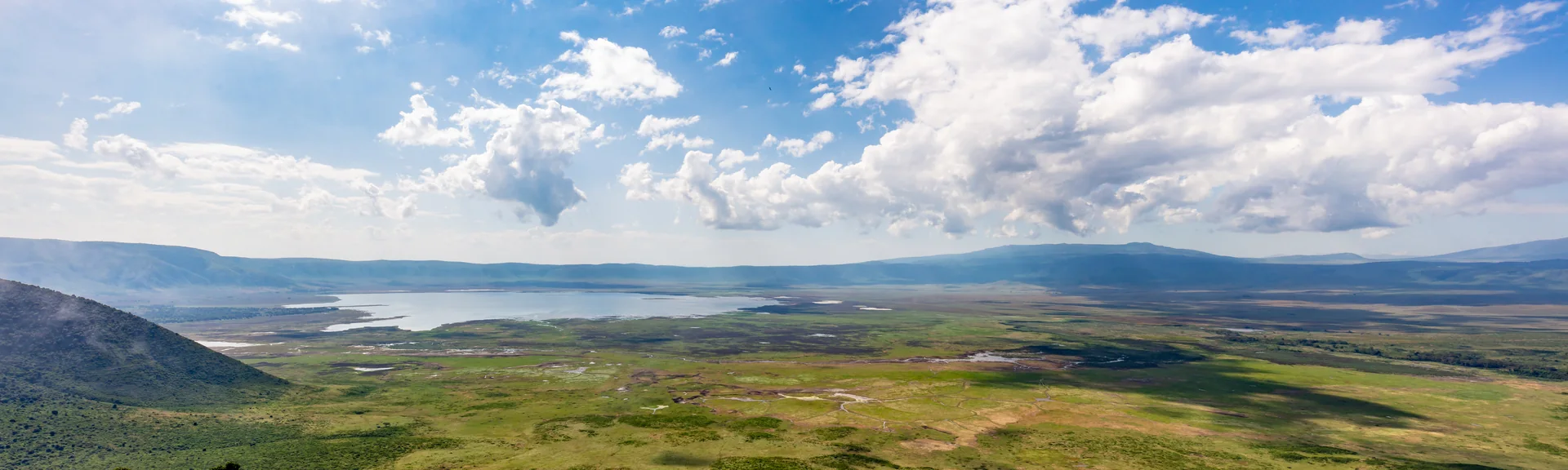 Panorama da Área de Conservação de Ngorongoro, com relevo, água e vegetação.