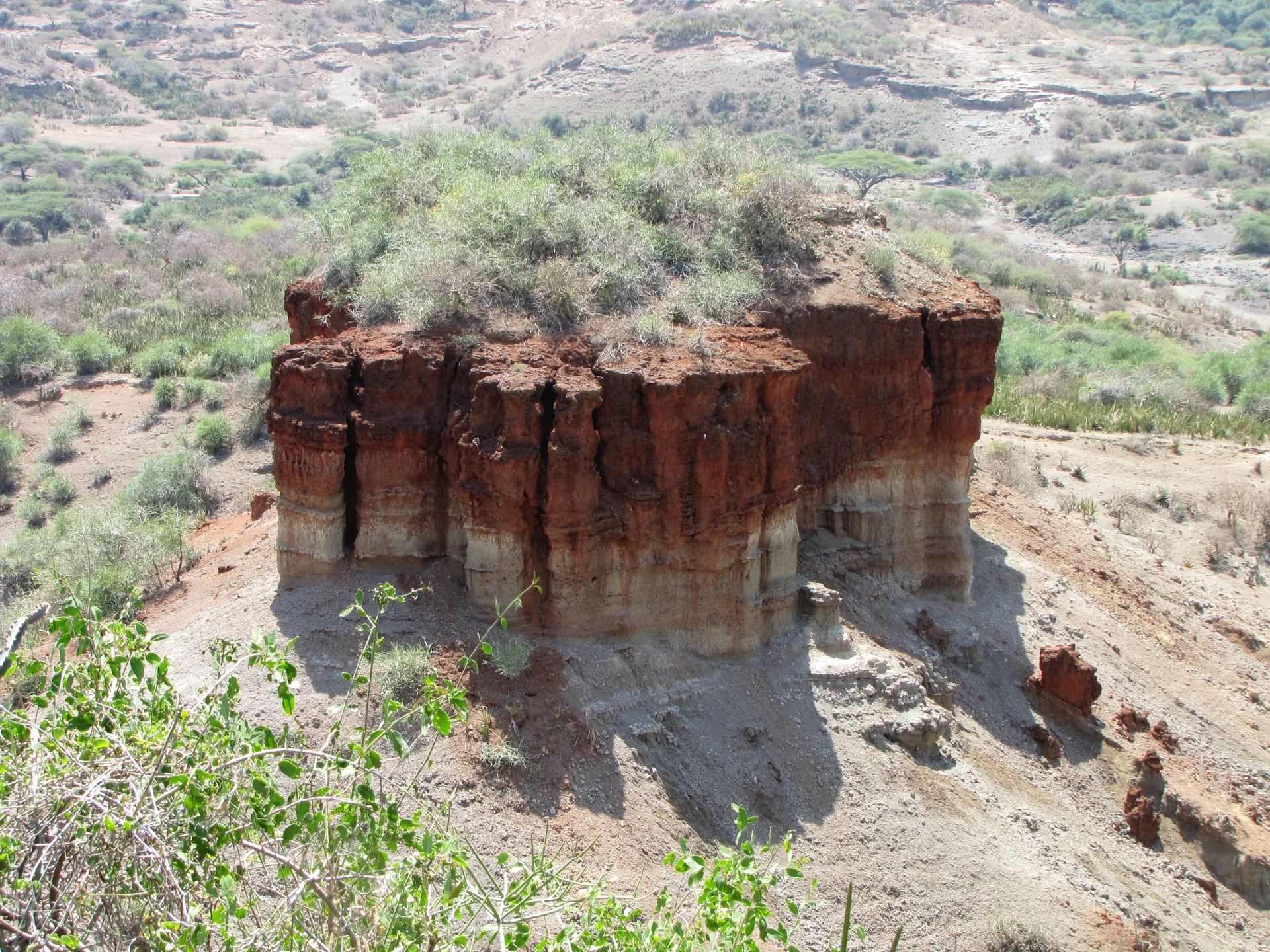 Formação rochosa em Oldupai Gorge, na Tanzânia, vista em meio a vegetação baixa.