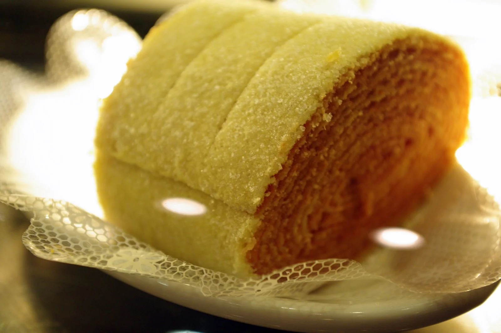Bolo de rolo inteiro e fatias servidos em prato branco.