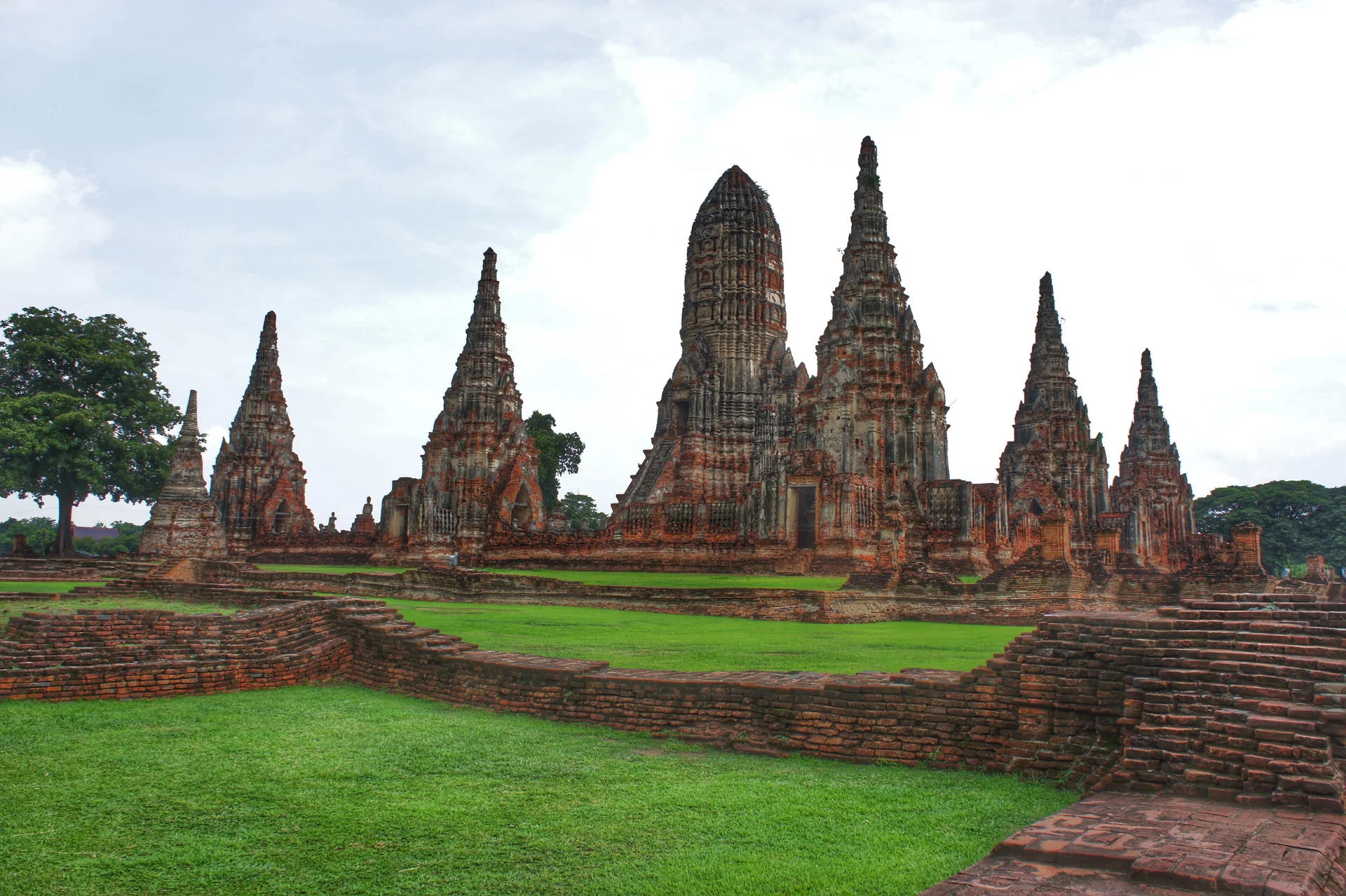 Wat Chaiwatthanaram em Ayutthaya, com prangs de tijolo, gramado e céu claro durante o dia.