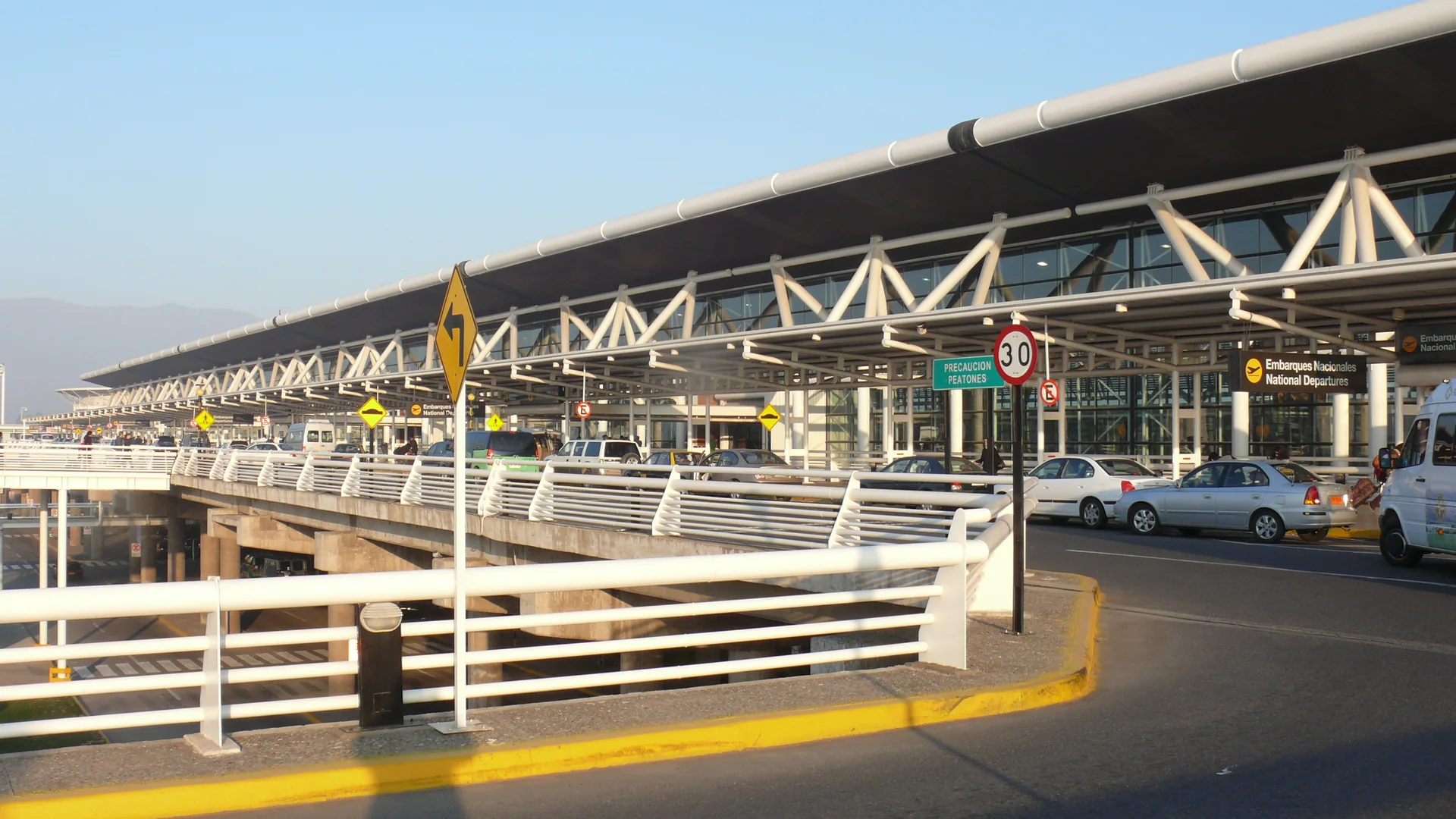 Fachada do terminal de passageiros do Aeroporto Internacional Arturo Merino Benítez, em Santiago, sob céu claro.