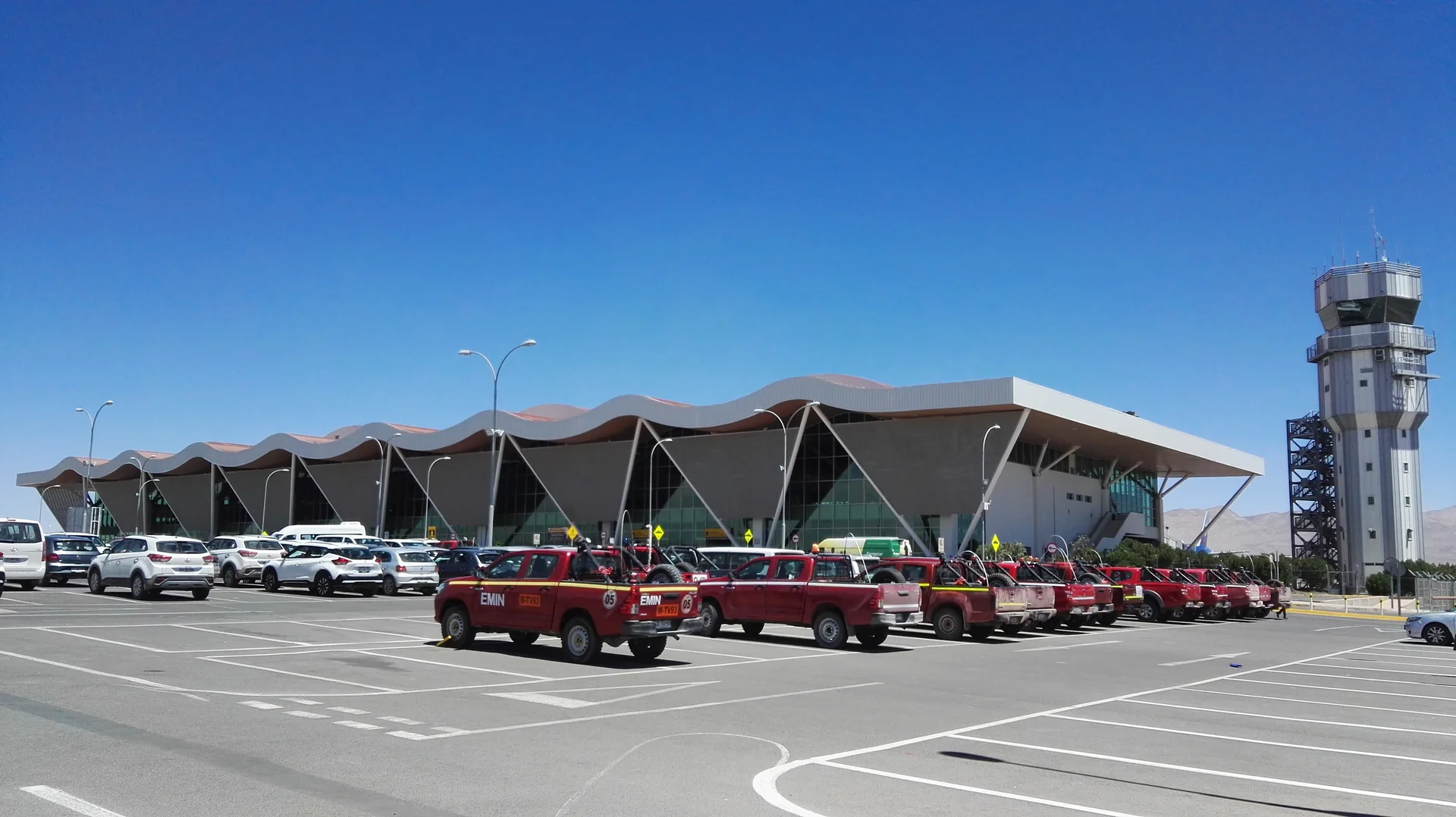 Terminal e torre do Aeroporto El Loa, em Calama, sob céu azul intenso.