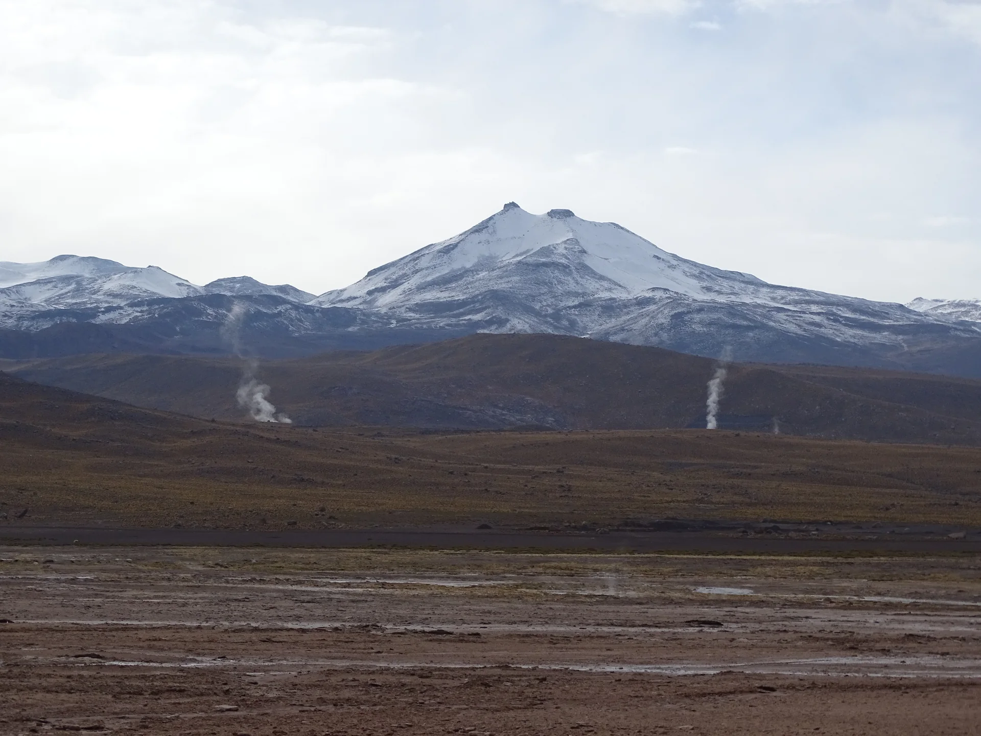 Fumarolas de El Tatio diante de montanhas do altiplano chileno.