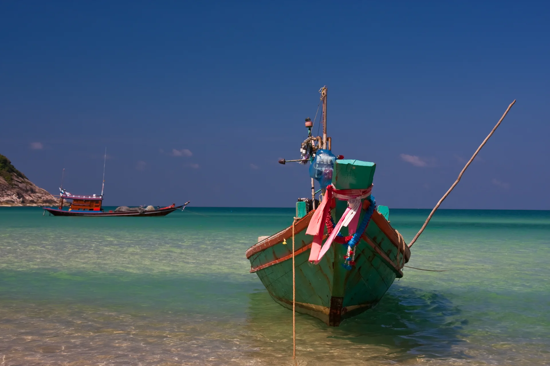 Barco longtail ancorado na areia de Bottle Beach, em Koh Pha Ngan, sob céu azul e mar verde-azulado.