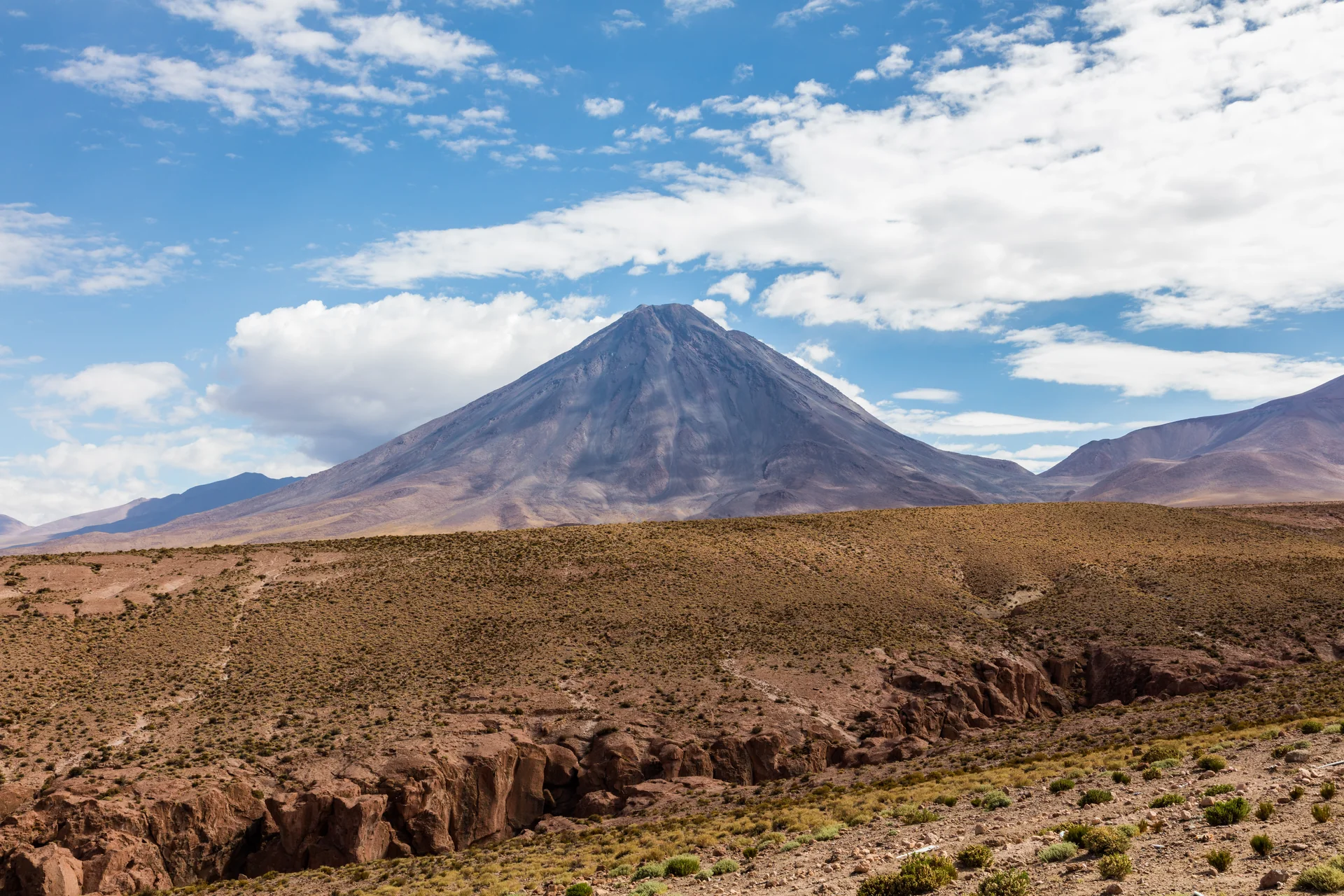 Vista diurna de San Pedro de Atacama e do vulcão Licancabur sob céu azul e claro.