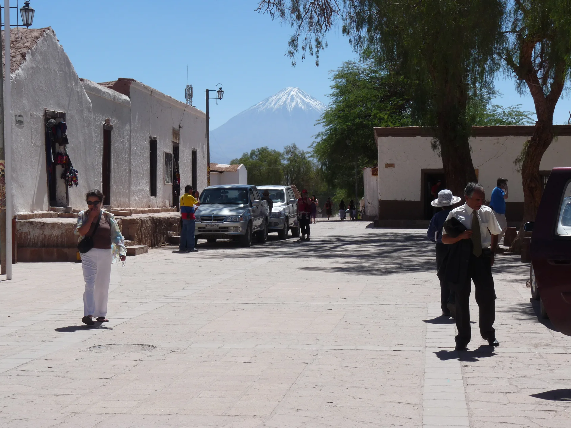 Vista diurna de San Pedro de Atacama com o vulcão Licancabur ao fundo, céu azul e paisagem desértica iluminada.