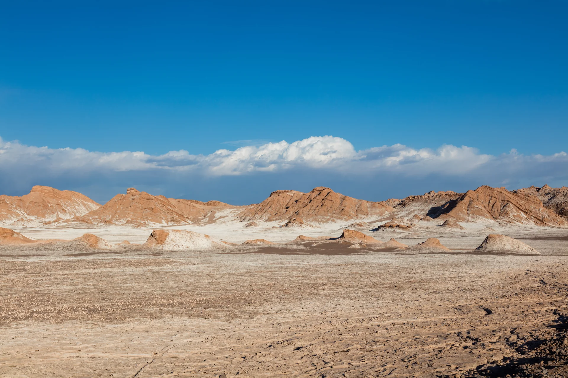 Formações rochosas claras e alaranjadas no Valle de la Luna, perto de San Pedro de Atacama, sob céu azul.