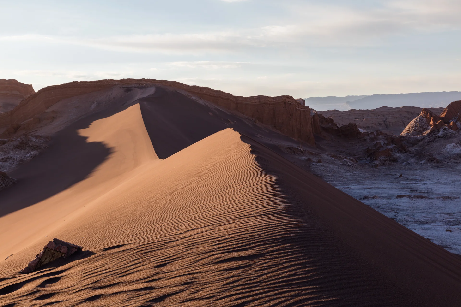 Duna Mayor de areia escura e dourada diante de paredões áridos no Valle de la Luna.