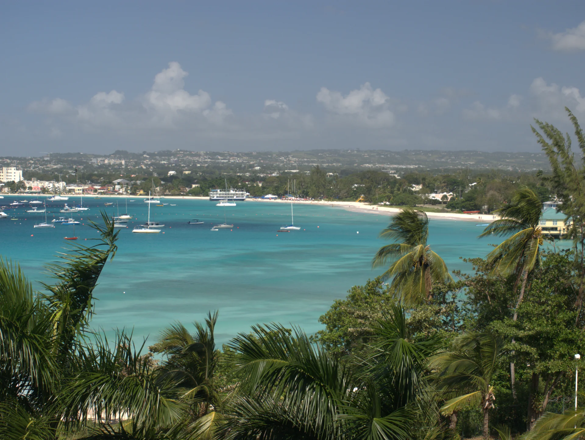 Vista de Carlisle Bay, com mar azul, vegetação em primeiro plano e Bridgetown à esquerda.
