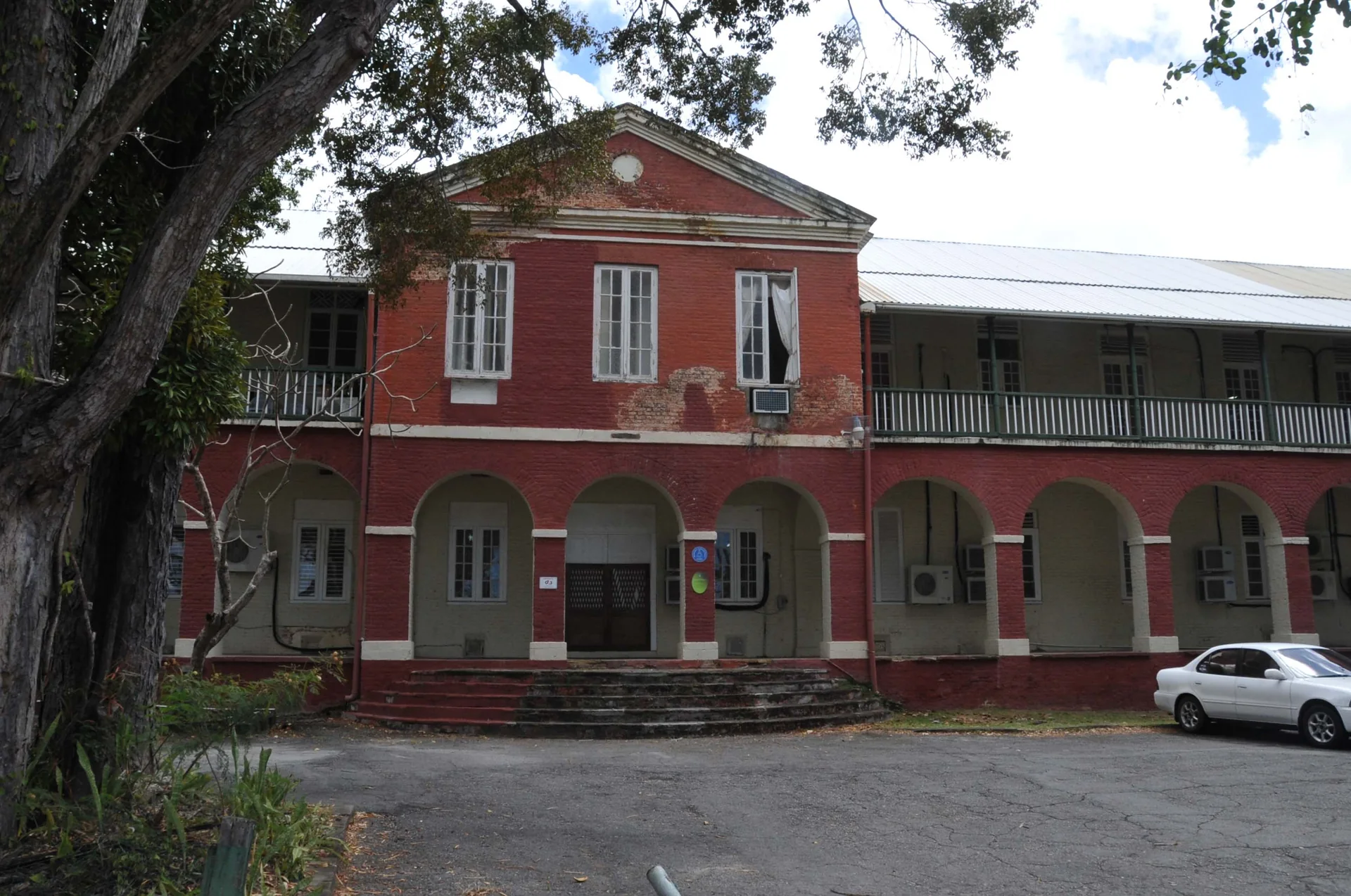 Fachada dos Soldiers’ Brick Barracks, edifício histórico de tijolos no distrito Garrison, em Bridgetown, Barbados, sob luz do dia.