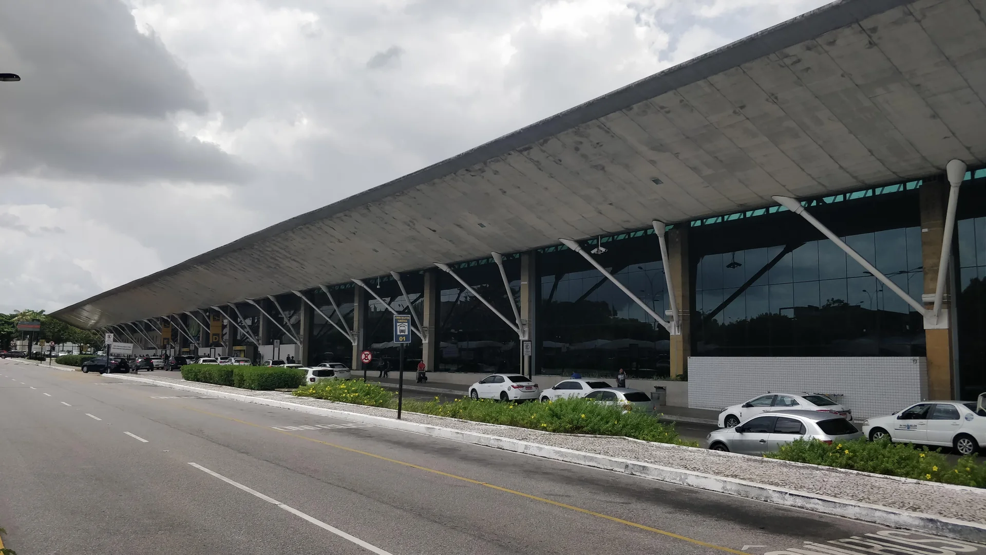 Fachada do Aeroporto Internacional de Belém em dia claro, com a cobertura do terminal em primeiro plano.