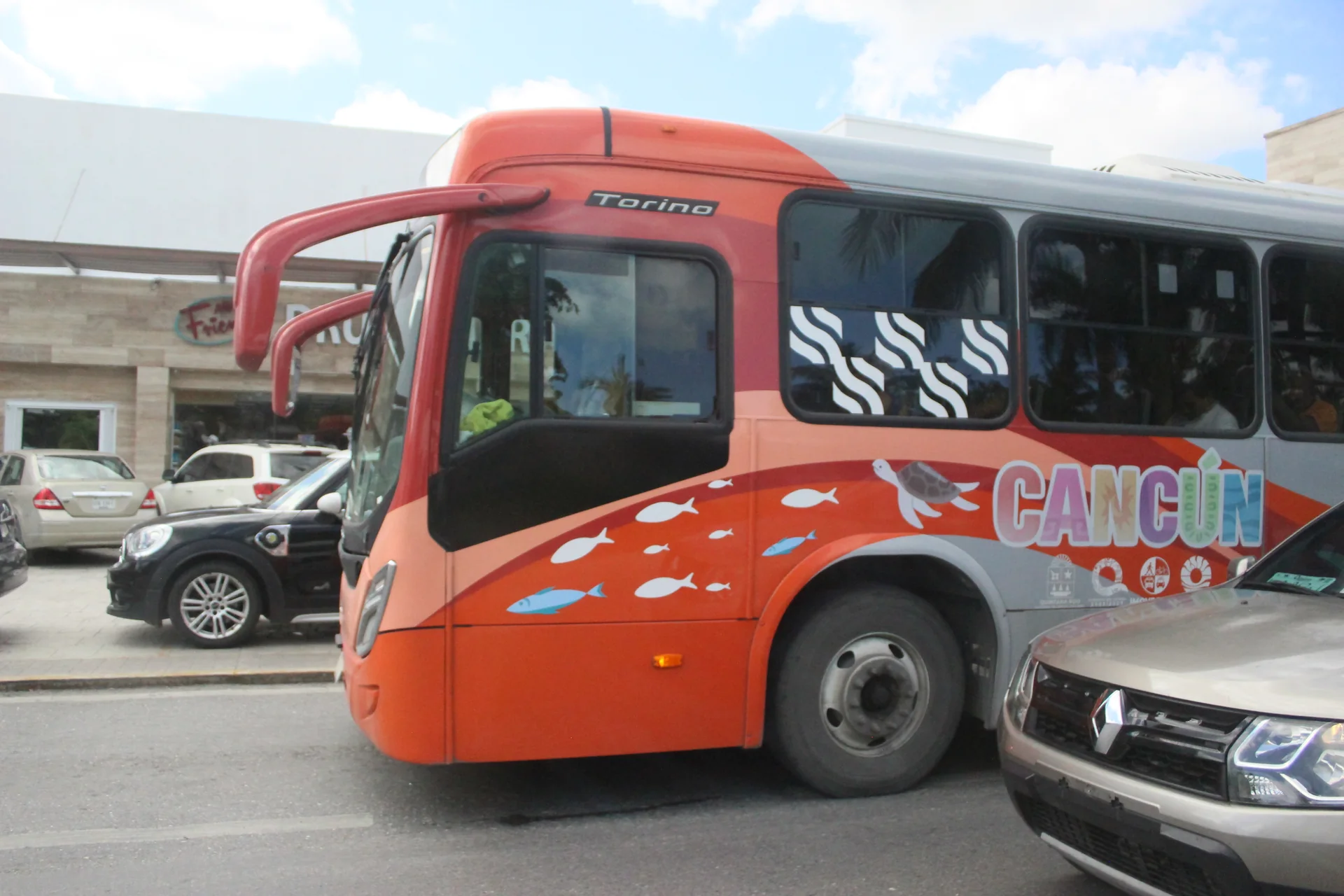 Ônibus urbano em circulação no trecho norte do Boulevard Kukulcán, em Cancún, sob luz natural pela manhã.