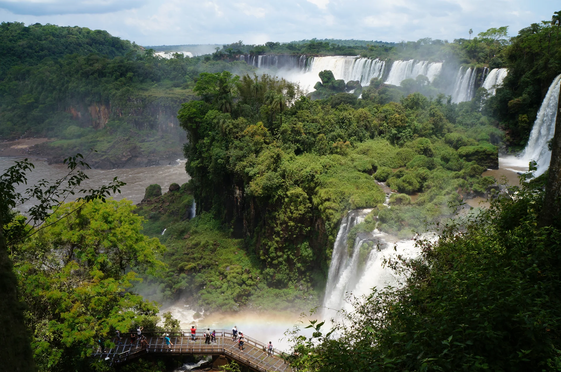 Vista ampla do Circuito Superior do Parque Nacional Iguazú, na Argentina, com quedas, mata e passarela ao fundo.