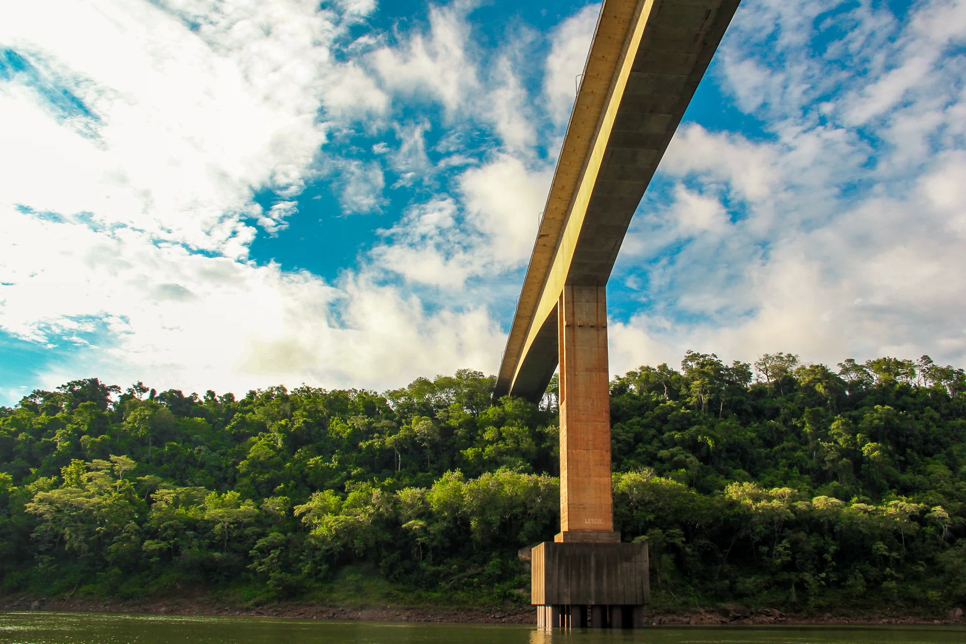 Ponte Internacional Tancredo Neves vista de baixo, sobre o rio e a vegetação da fronteira entre Brasil e Argentina.