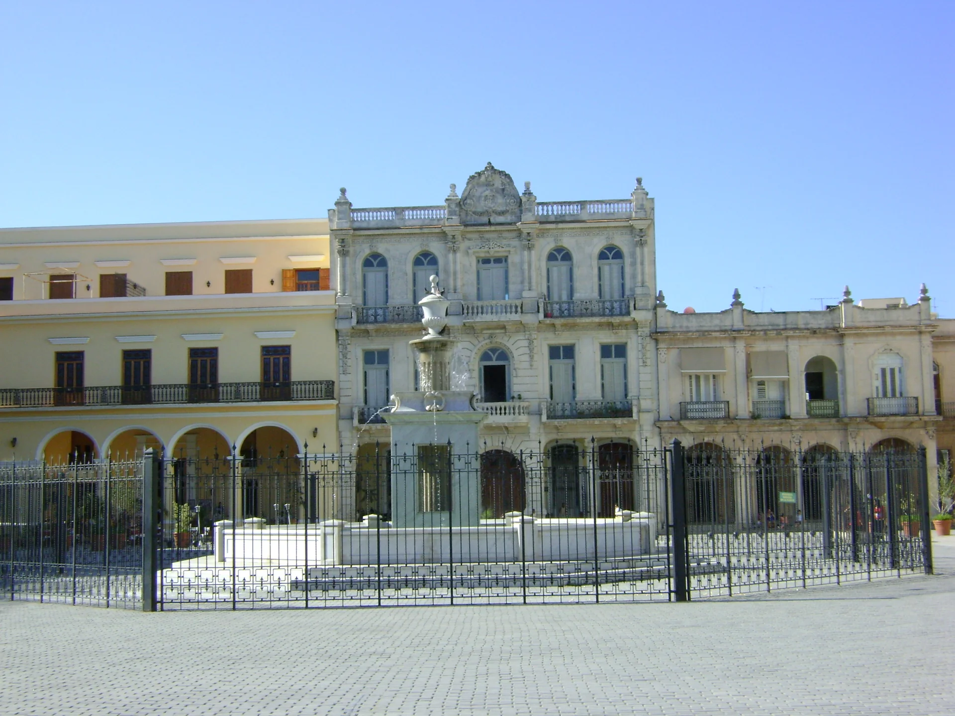 Fachadas históricas e fonte da Plaza Vieja, em Habana Vieja, sob céu azul durante o dia.