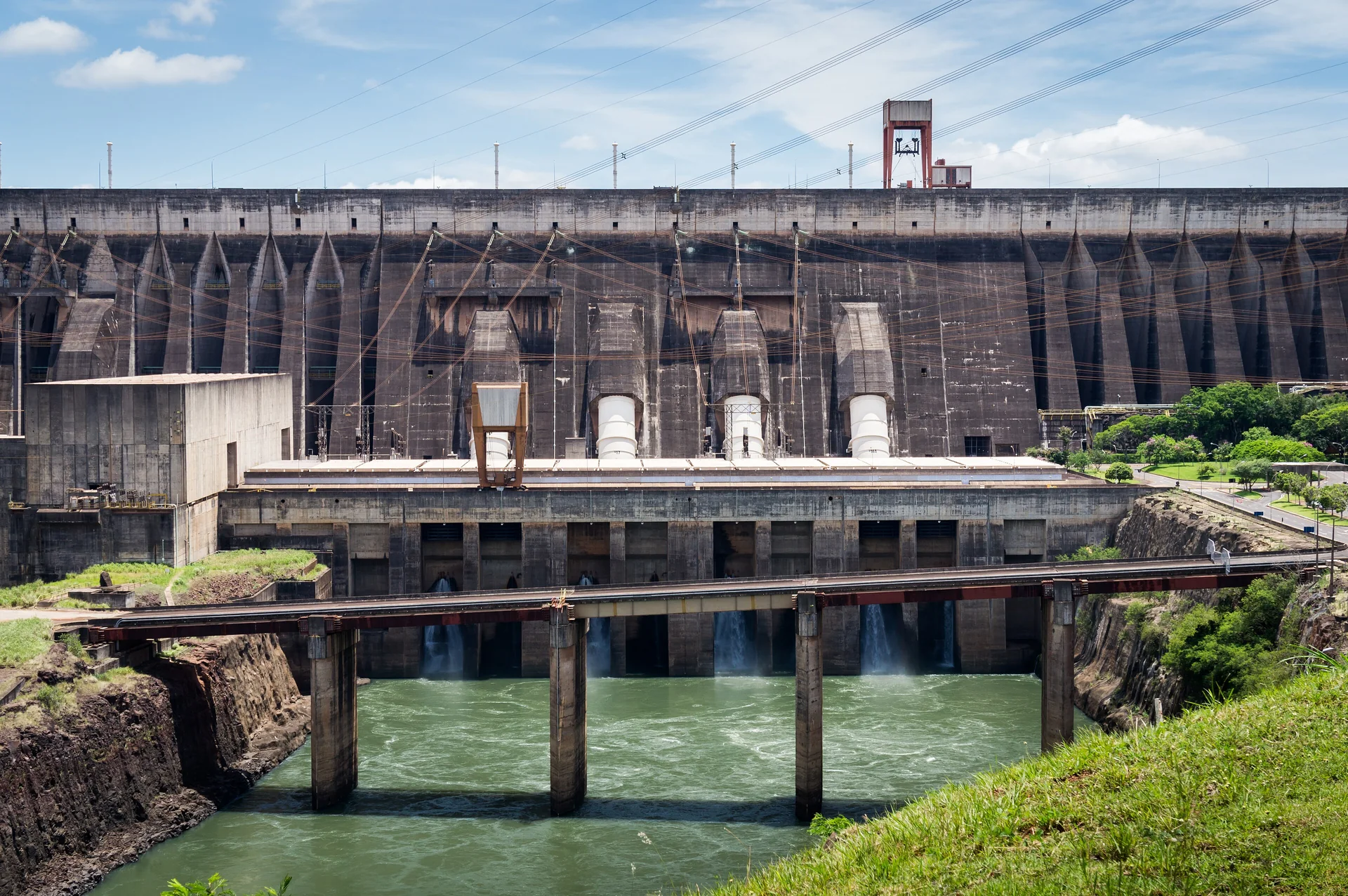 Fachada da barragem da Usina Hidrelétrica de Itaipu em luz diurna, junto ao Rio Paraná.