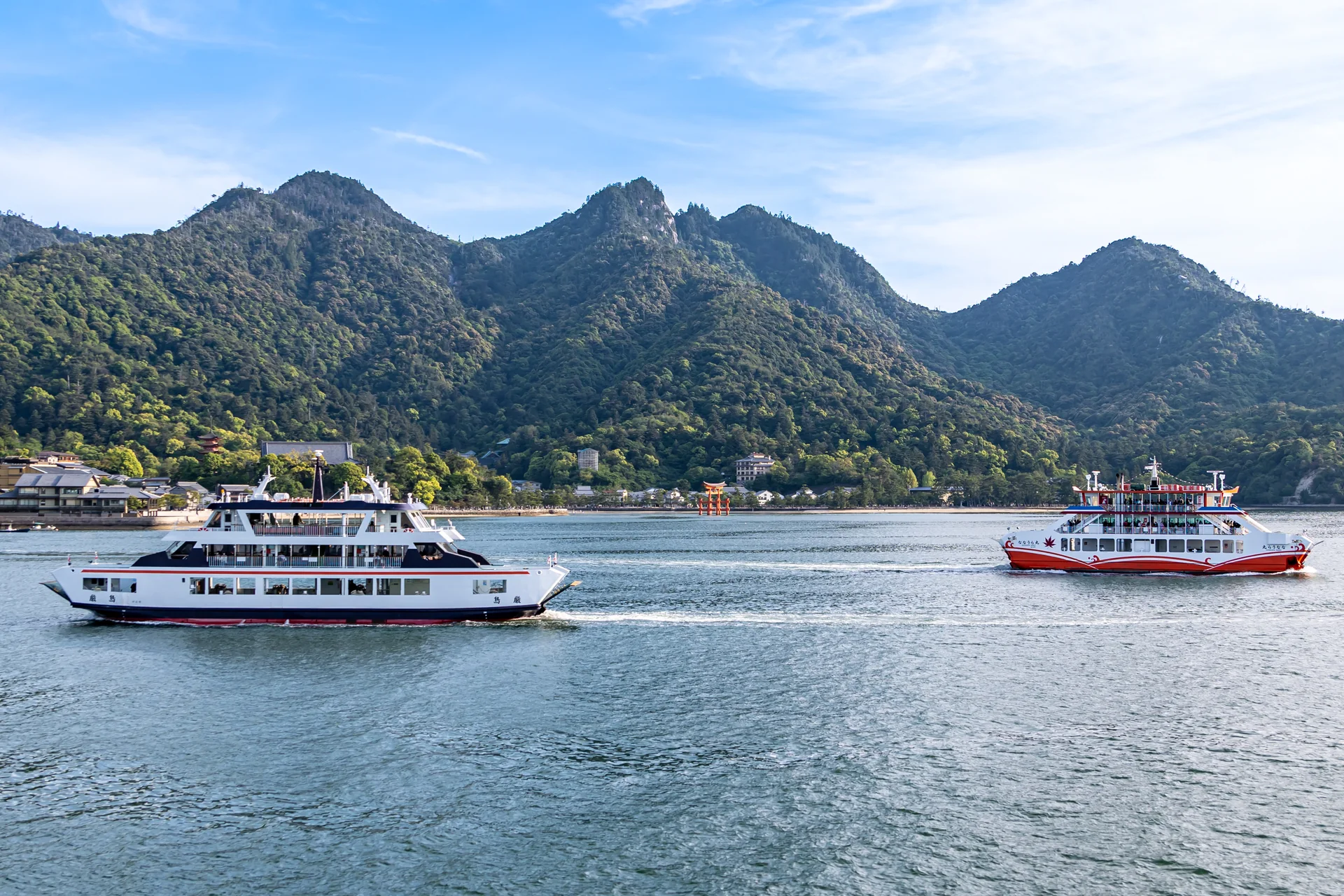 Ferries na rota de Miyajima, com o grande torii de Itsukushima e o Monte Misen vistos do mar em luz diurna.