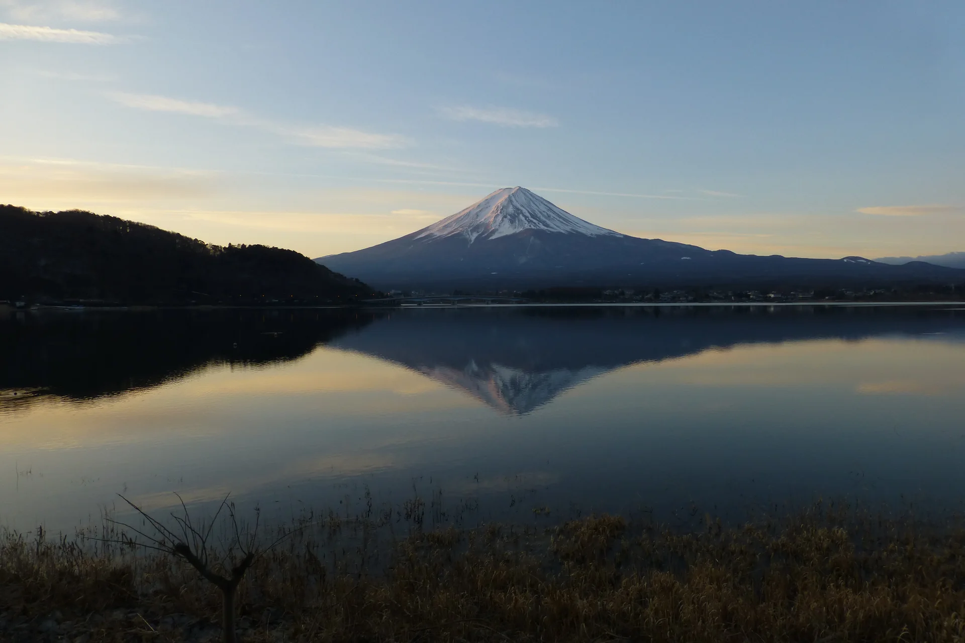 Monte Fuji refletido no Lago Kawaguchi, em manhã de céu aberto e luz suave.