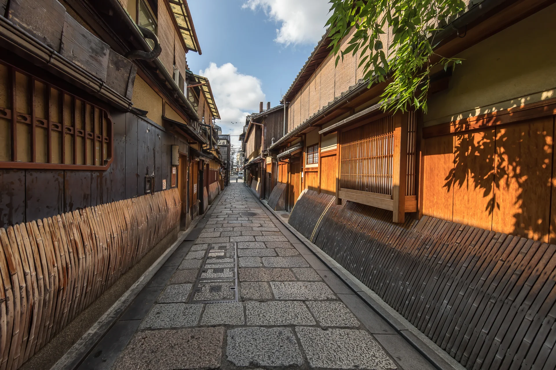 Rua de pedestres pavimentada em Gion, com fachadas de madeira e bambu, sem pessoas em primeiro plano.