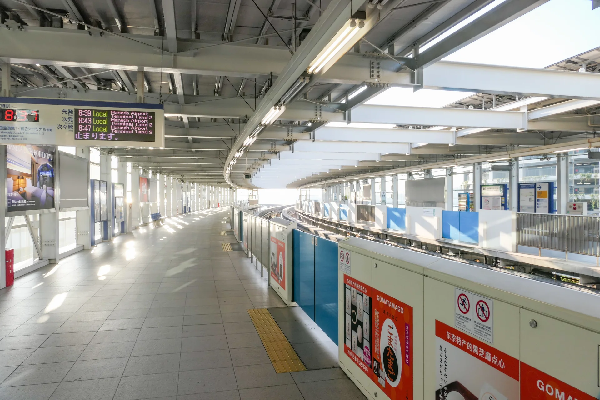 Plataformas da estação do Monotrilho de Tóquio no Terminal 3 de Haneda, iluminadas por luz natural.
