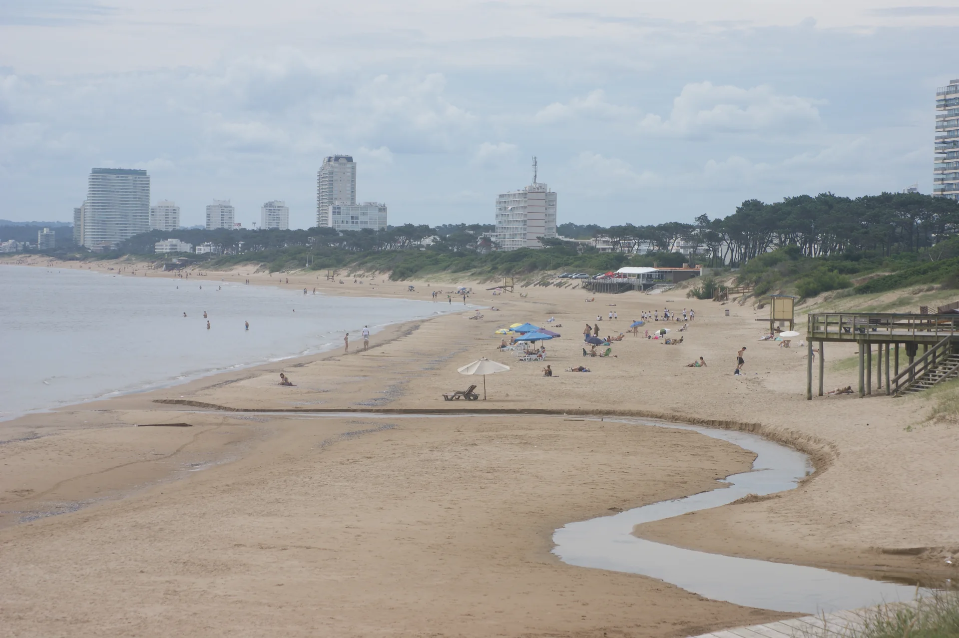 Faixa de areia e mar na Playa Mansa, em Punta del Este, com edifícios da península ao fundo.