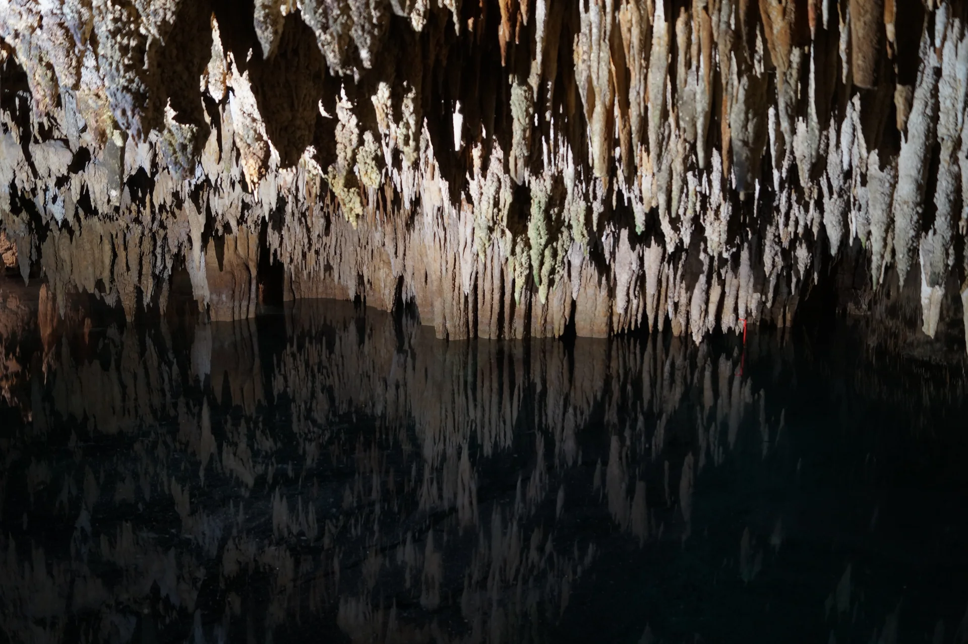 Formações de calcário se refletem na água escura de uma gruta no Cenote de Aktun Chen, em Quintana Roo.