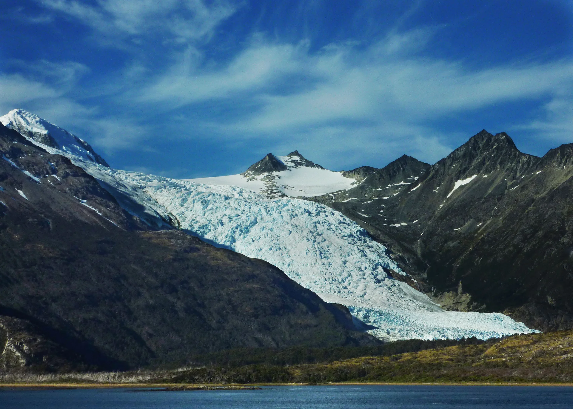 Canal de Beagle cercado por montanhas e geleiras sob luz natural, visto a partir da água.