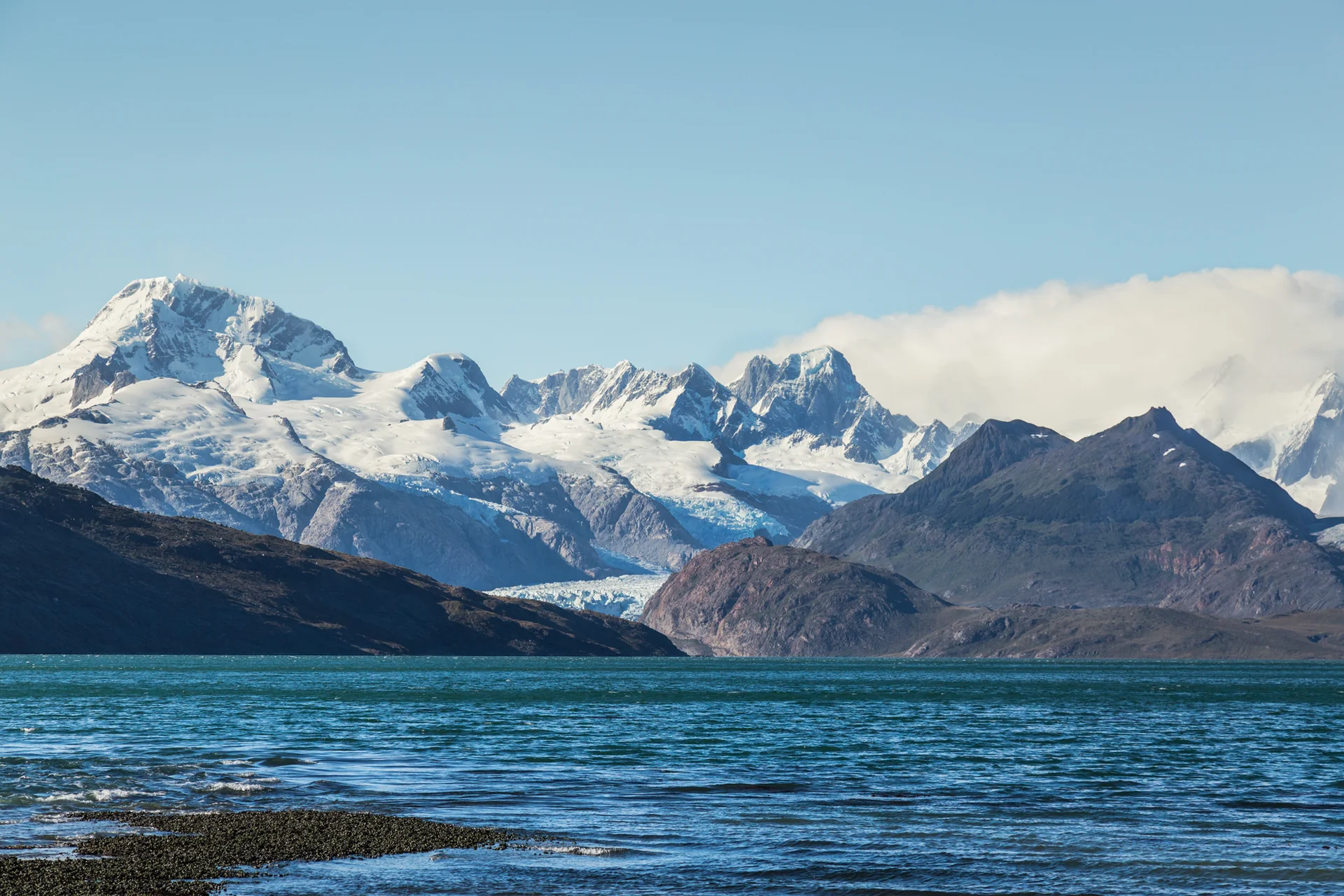 Glaciar Marinelli entre montanhas da Terra do Fogo, com água e vegetação sob luz natural.