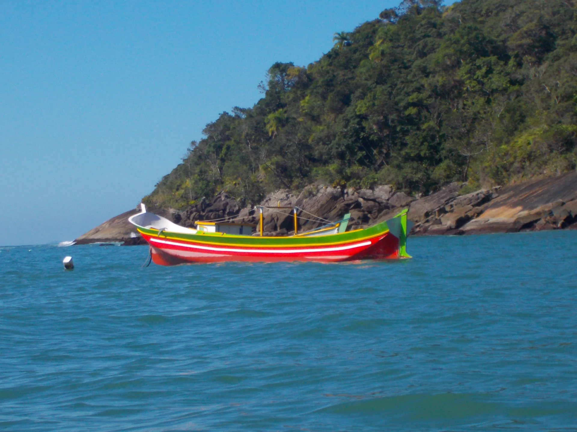 Canoa caiçara monóxila navegando diante da costa da Praia da Serraria, em Ilhabela.