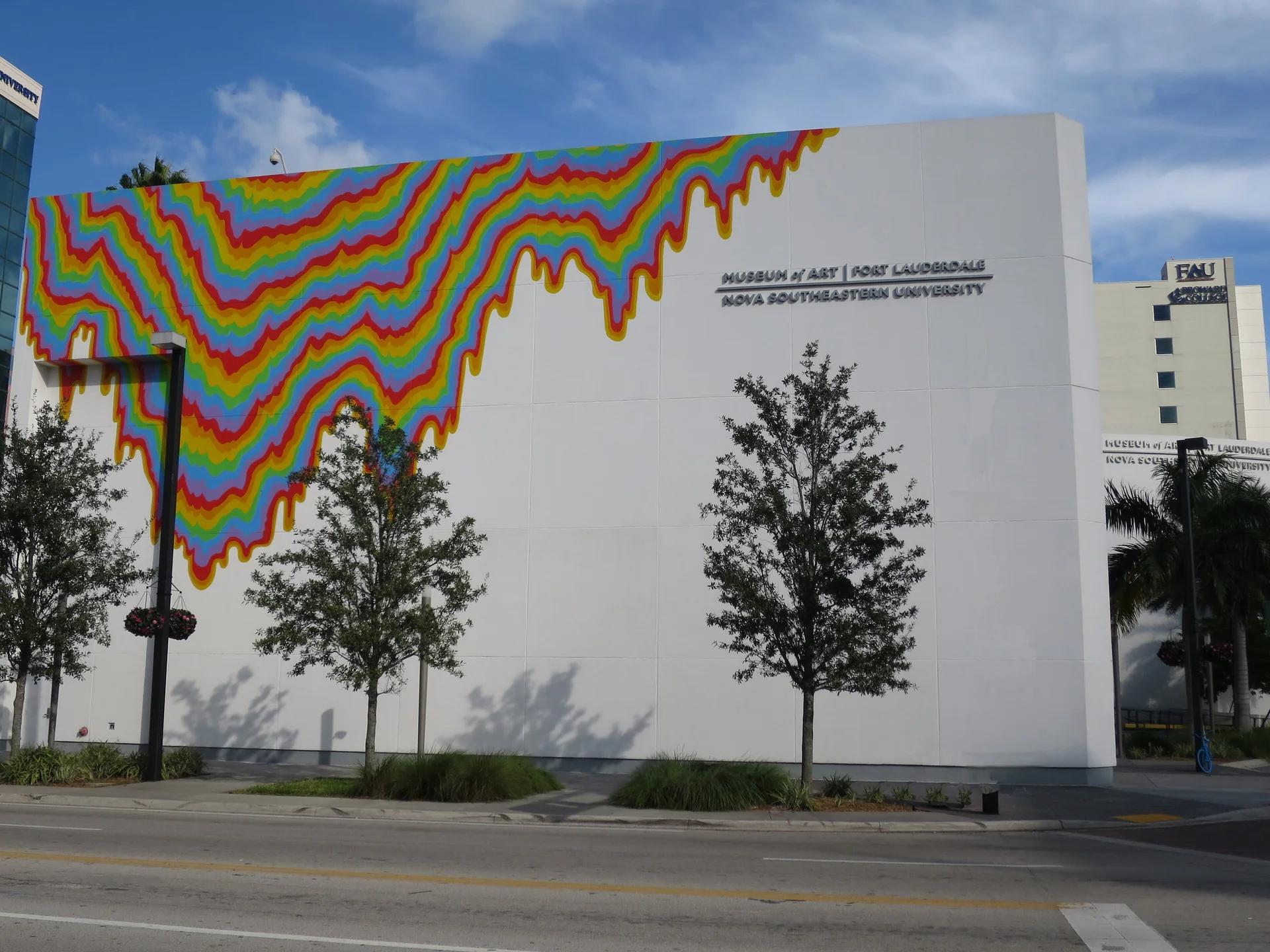 Fachada branca do Museum of Art Fort Lauderdale, atual NSU Art Museum, com instalação colorida, árvores e céu azul.