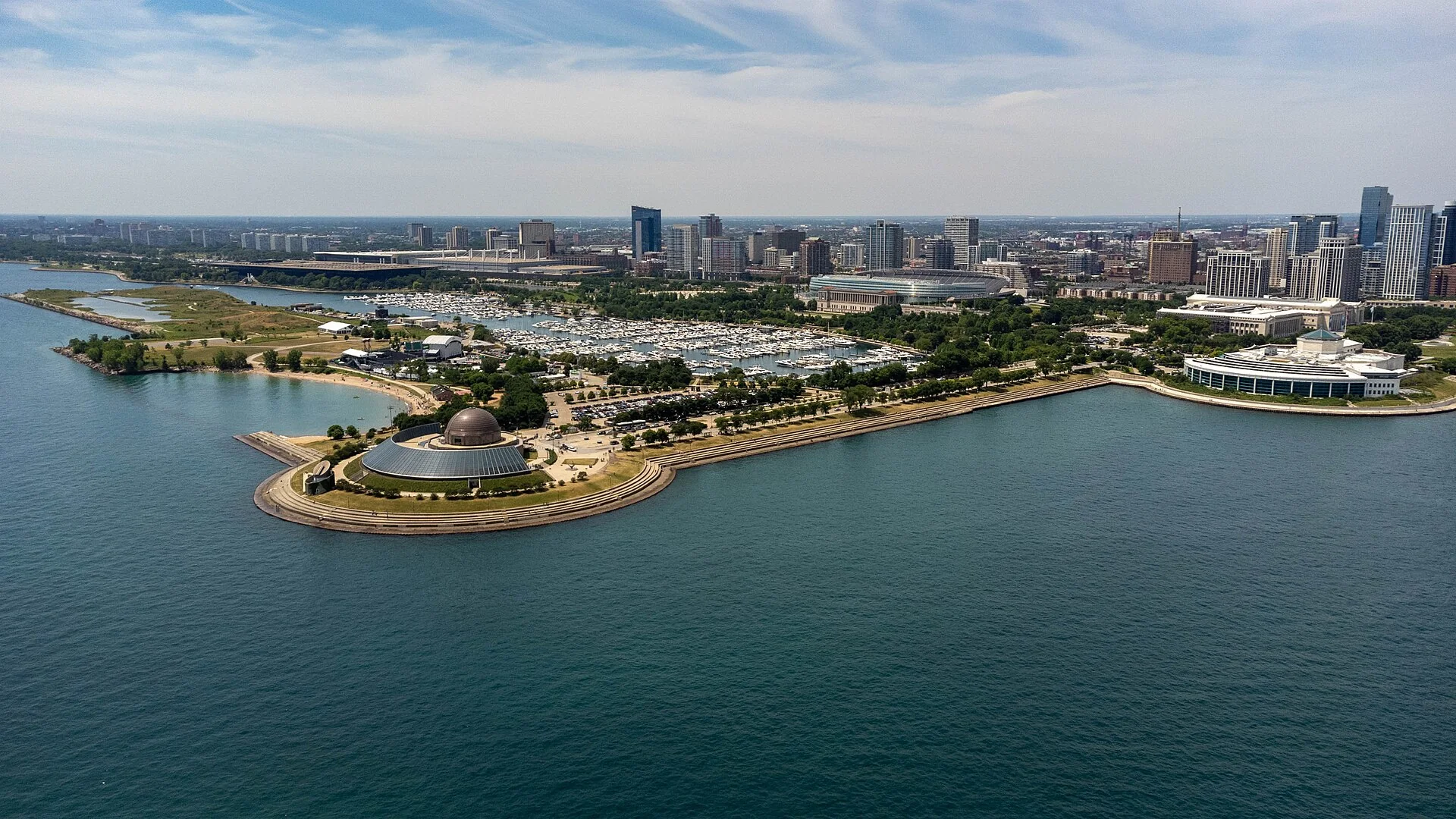 Vista aérea diurna do Museum Campus de Chicago, com o Adler Planetarium, a orla do Lake Michigan e a marina ao fundo.