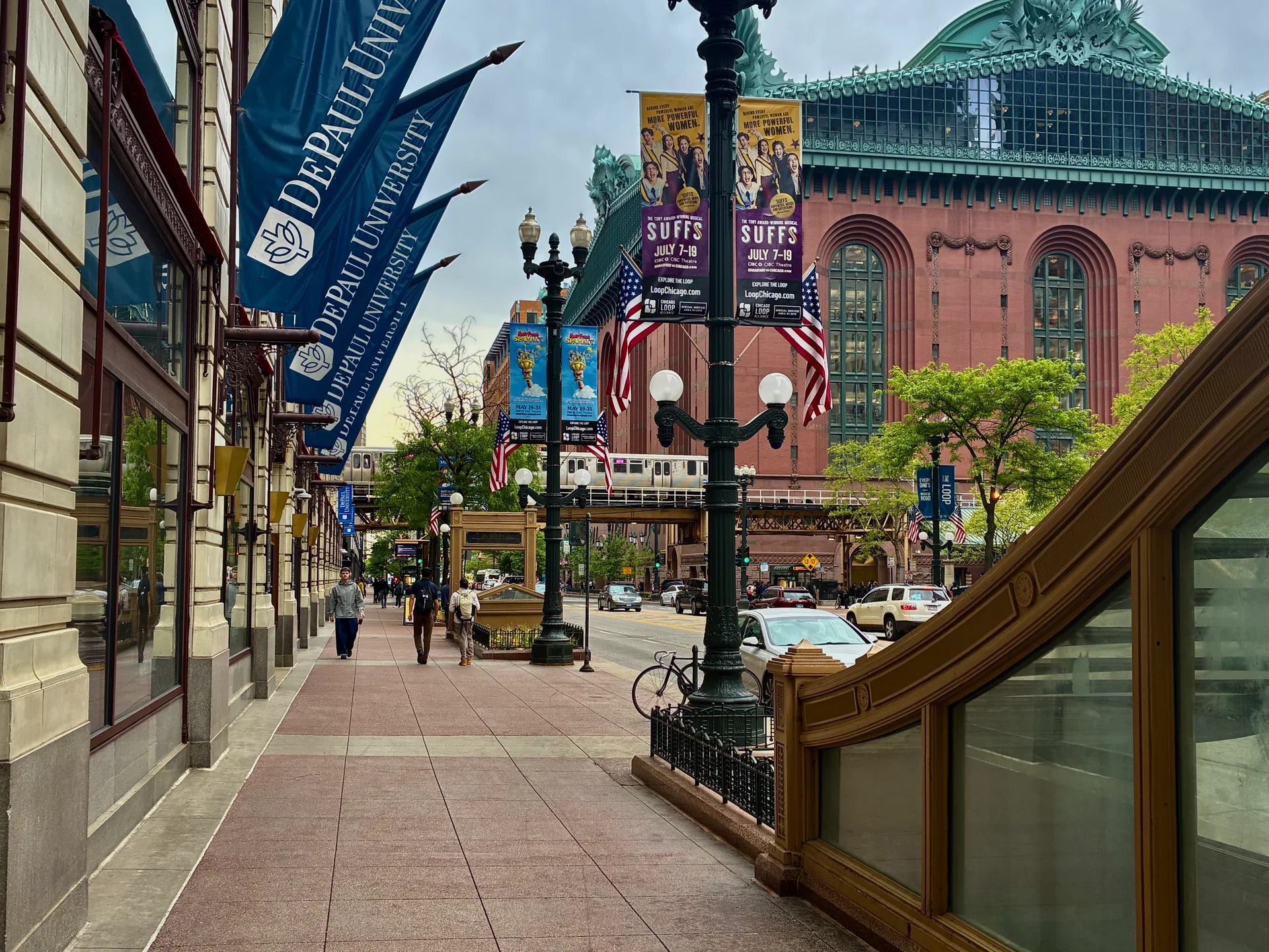 Vista diurna de uma rua do Loop em Chicago, com arquitetura urbana, pessoas na calçada e transporte público ao fundo.