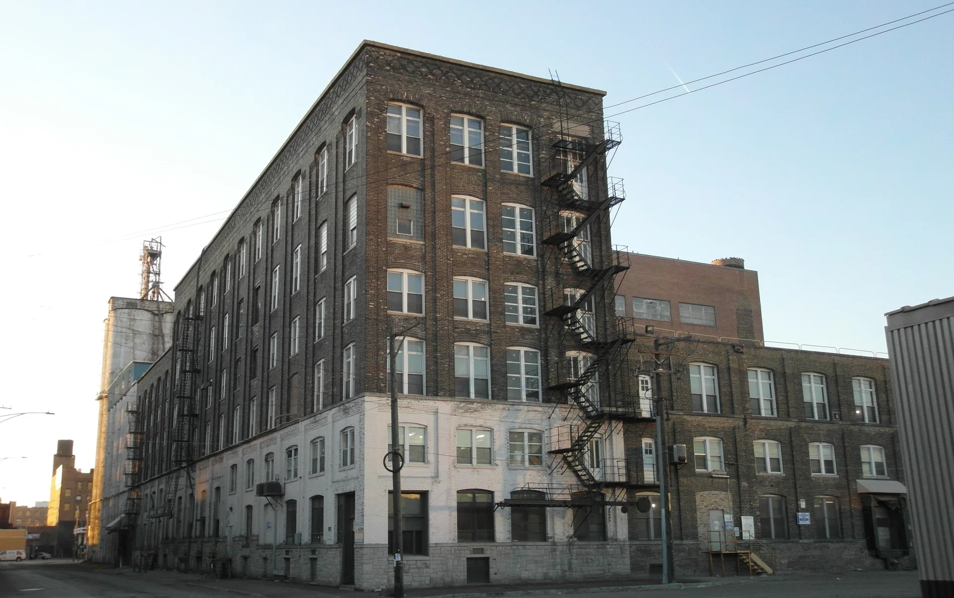 Edifício industrial de tijolos no Fulton Market, com escadas externas, sob céu claro no fim da tarde.