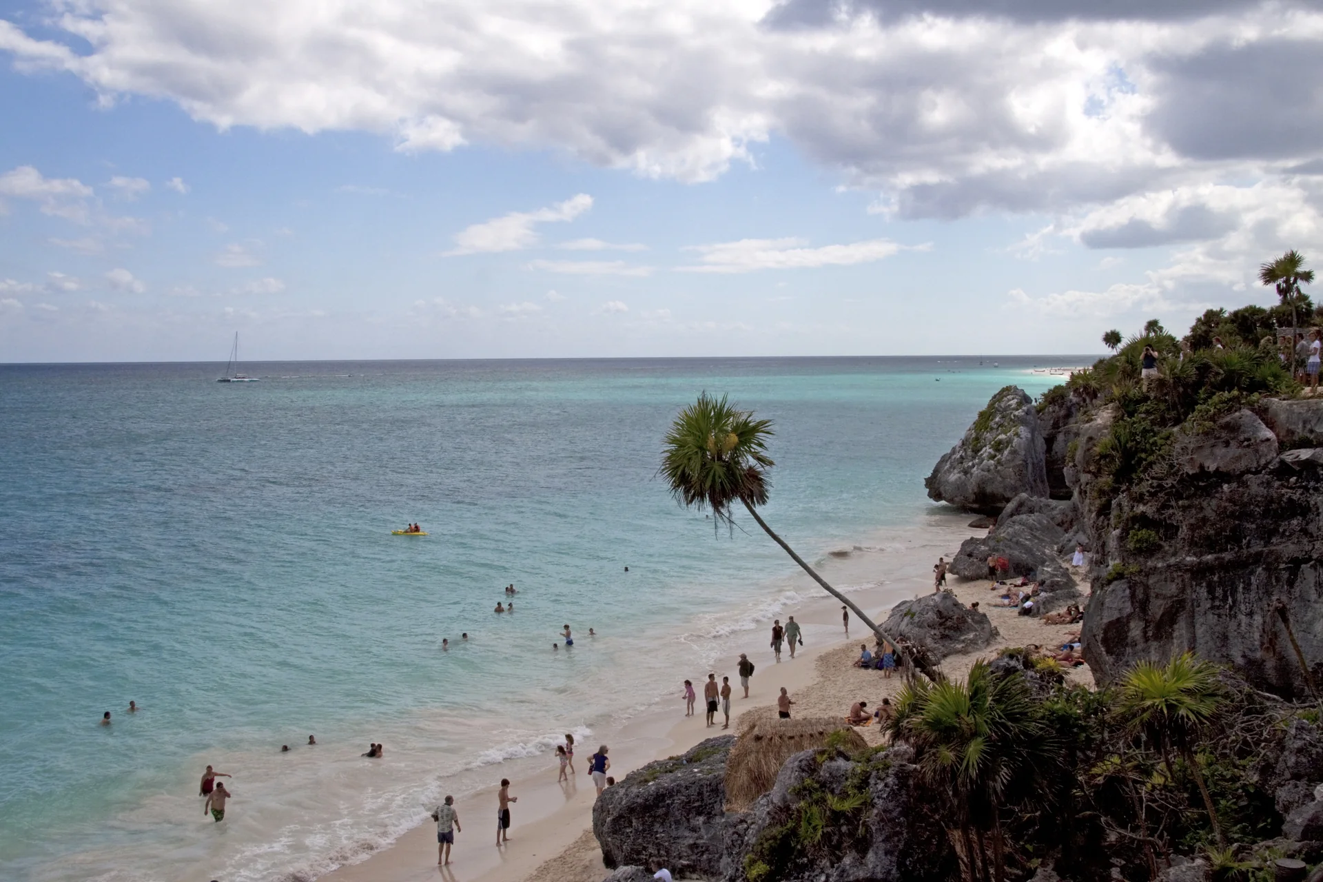 Praia de Puerto Morelos, em Quintana Roo, com mar do Caribe, areia clara e céu parcialmente nublado.