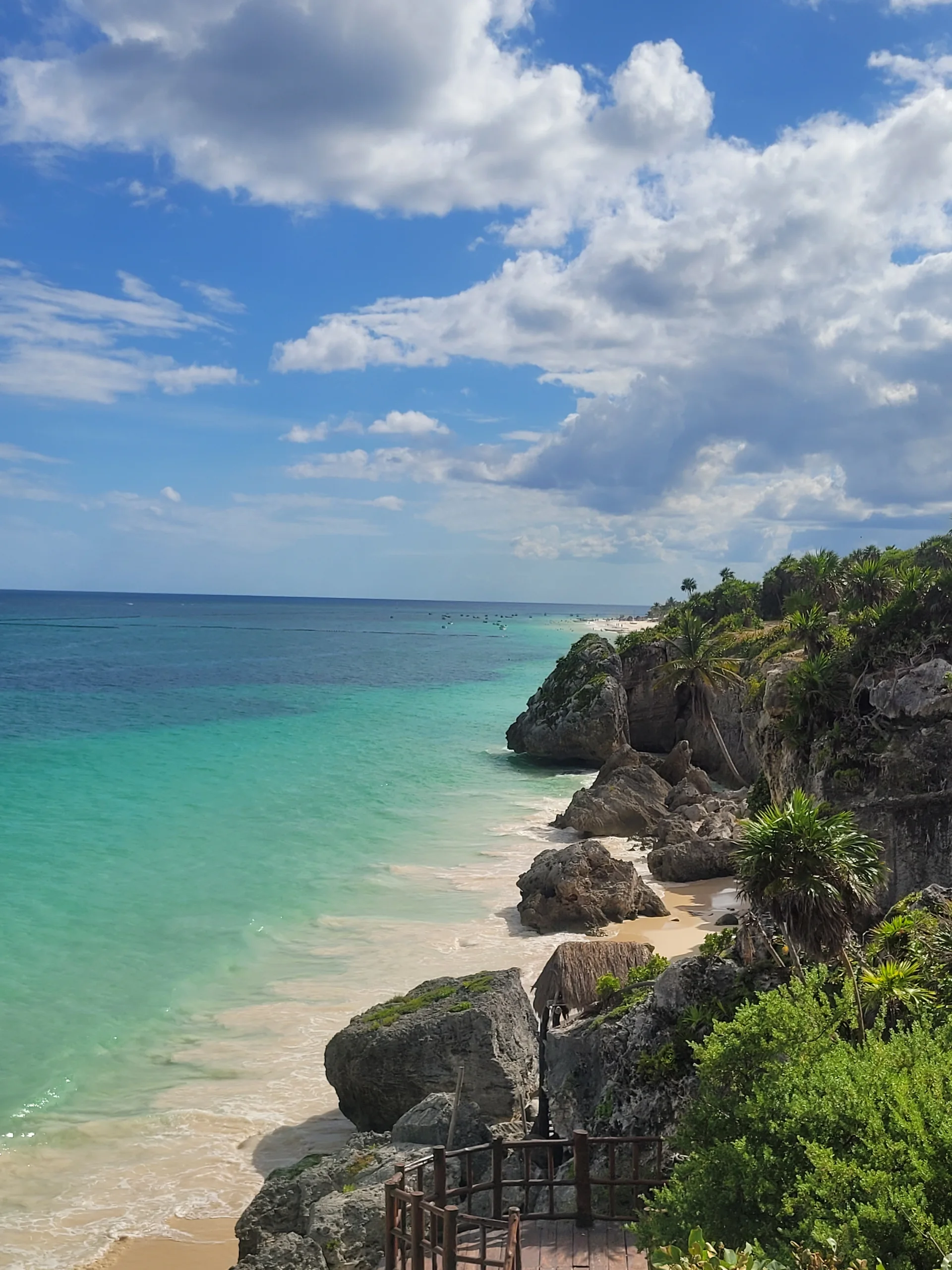 Vista vertical das ruínas maias de Tulum diante do mar Caribe e da vegetação costeira em dia claro.