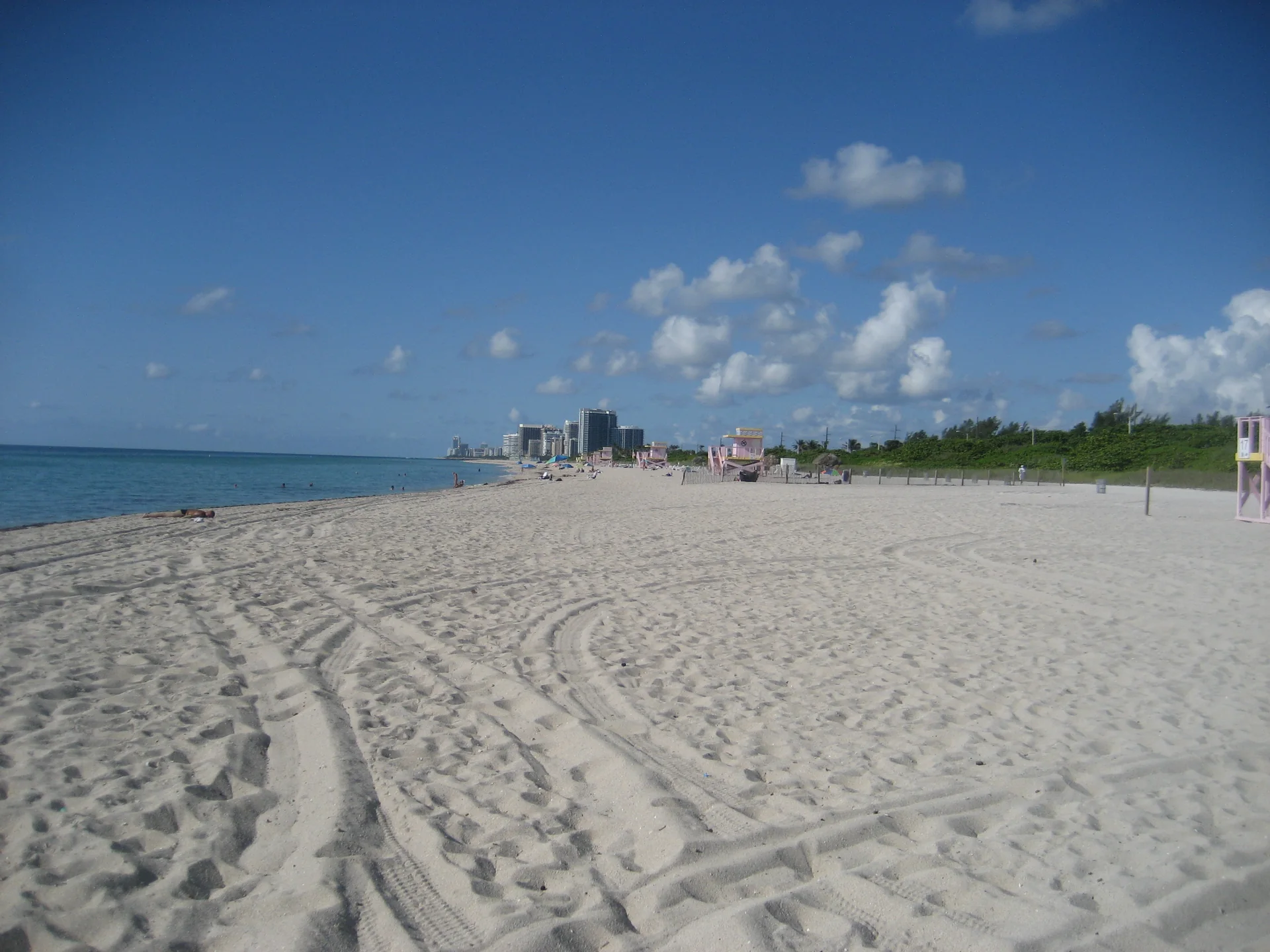 Vista ampla de Haulover Beach, em Miami-Dade ao norte de Bal Harbour, com faixa de areia, banhistas distantes, vegetação e oceano.