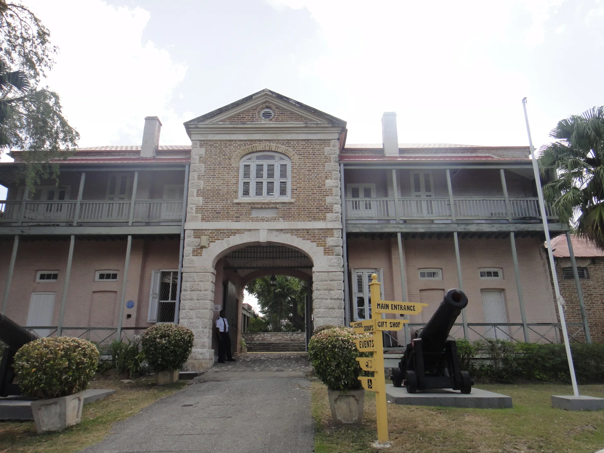 Fachada do Barbados Museum & Historical Society, antigo presídio militar, com canhões e placa de entrada em Bridgetown.