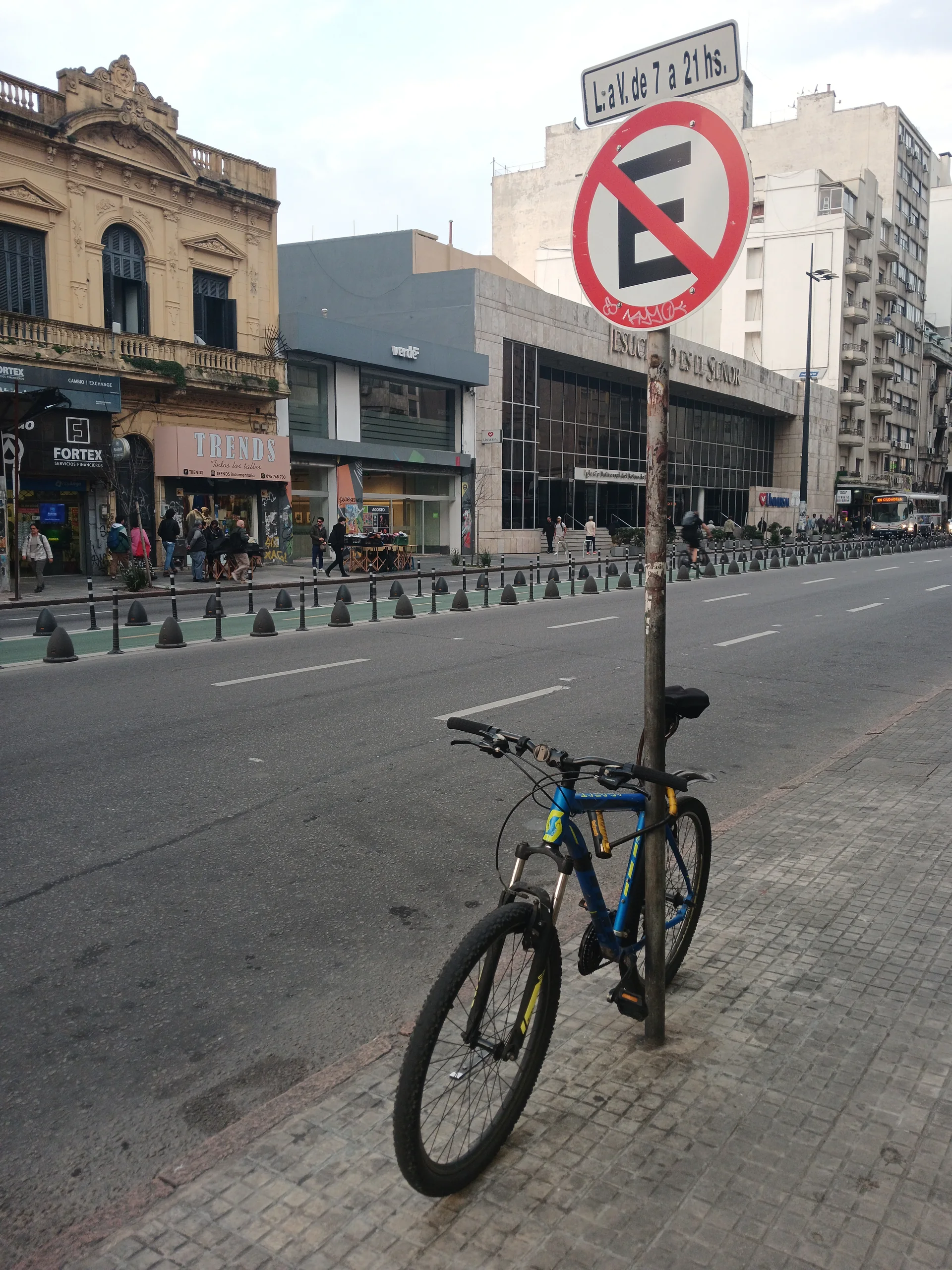 Bicicleta estacionada em uma avenida de Montevidéu, ao lado de uma placa de trânsito.