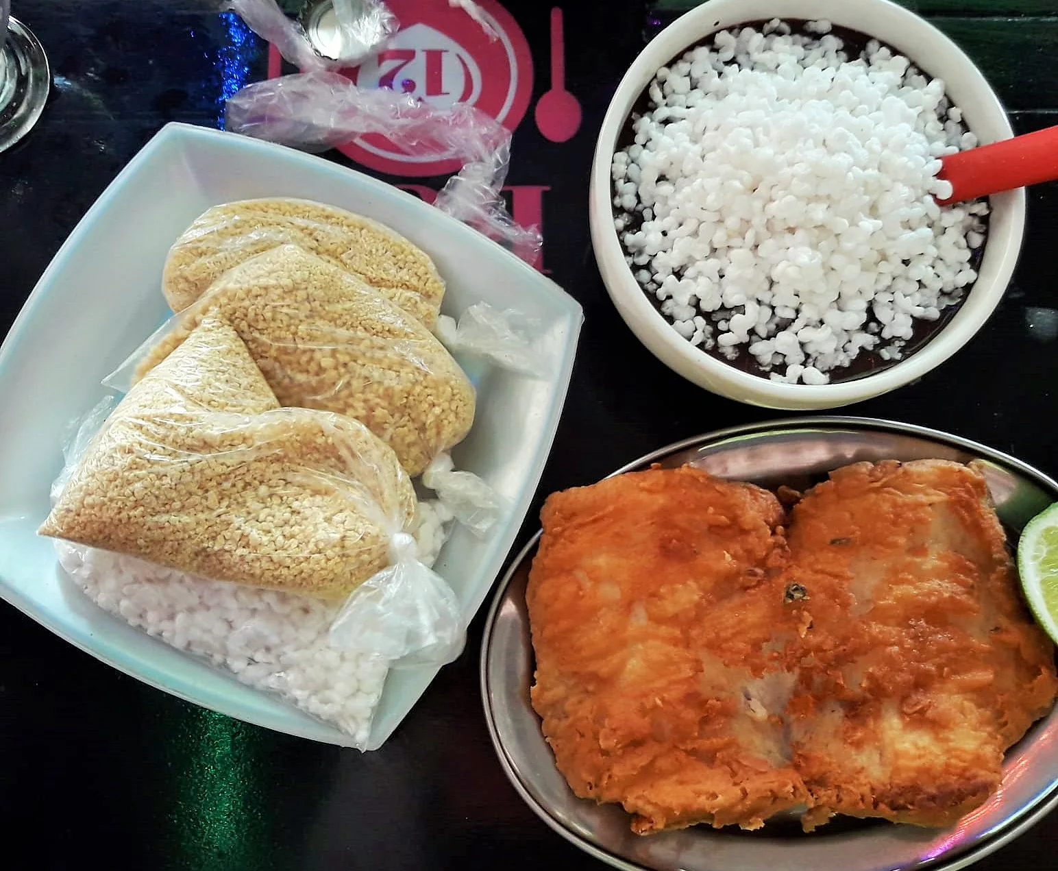 Tigela de açaí ao lado de peixe frito e porções de farinha em uma refeição simples no Ver-o-Peso, em Belém.
