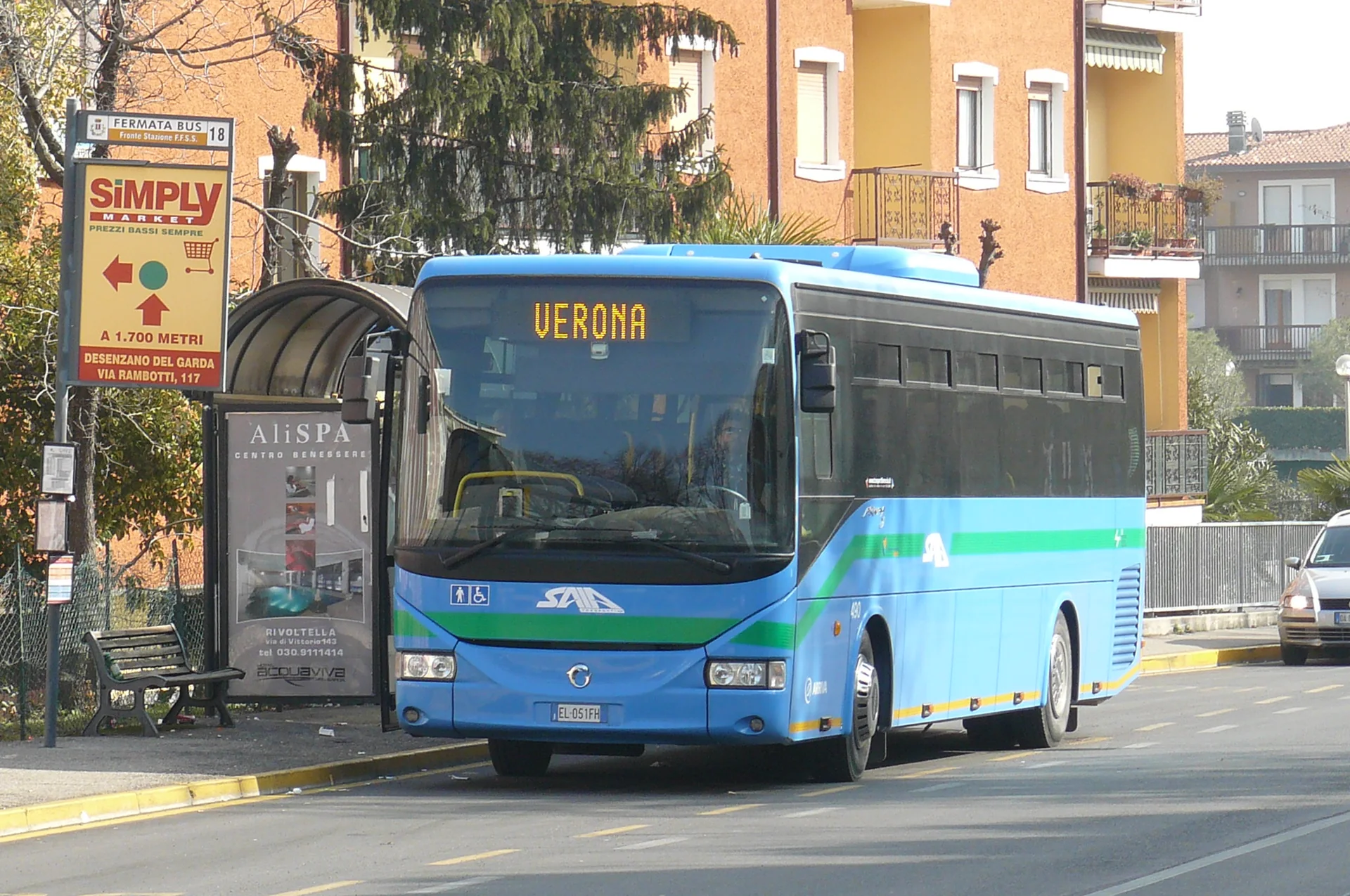 Ônibus regional azul parado em ponto de Desenzano del Garda, com placa de parada e letreiro para Verona.