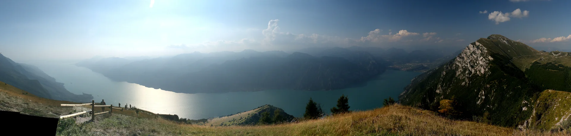 Panorama do Lago di Garda visto do Monte Baldo, com montanhas em primeiro plano e o lago se estendendo entre Riva e Sirmione.