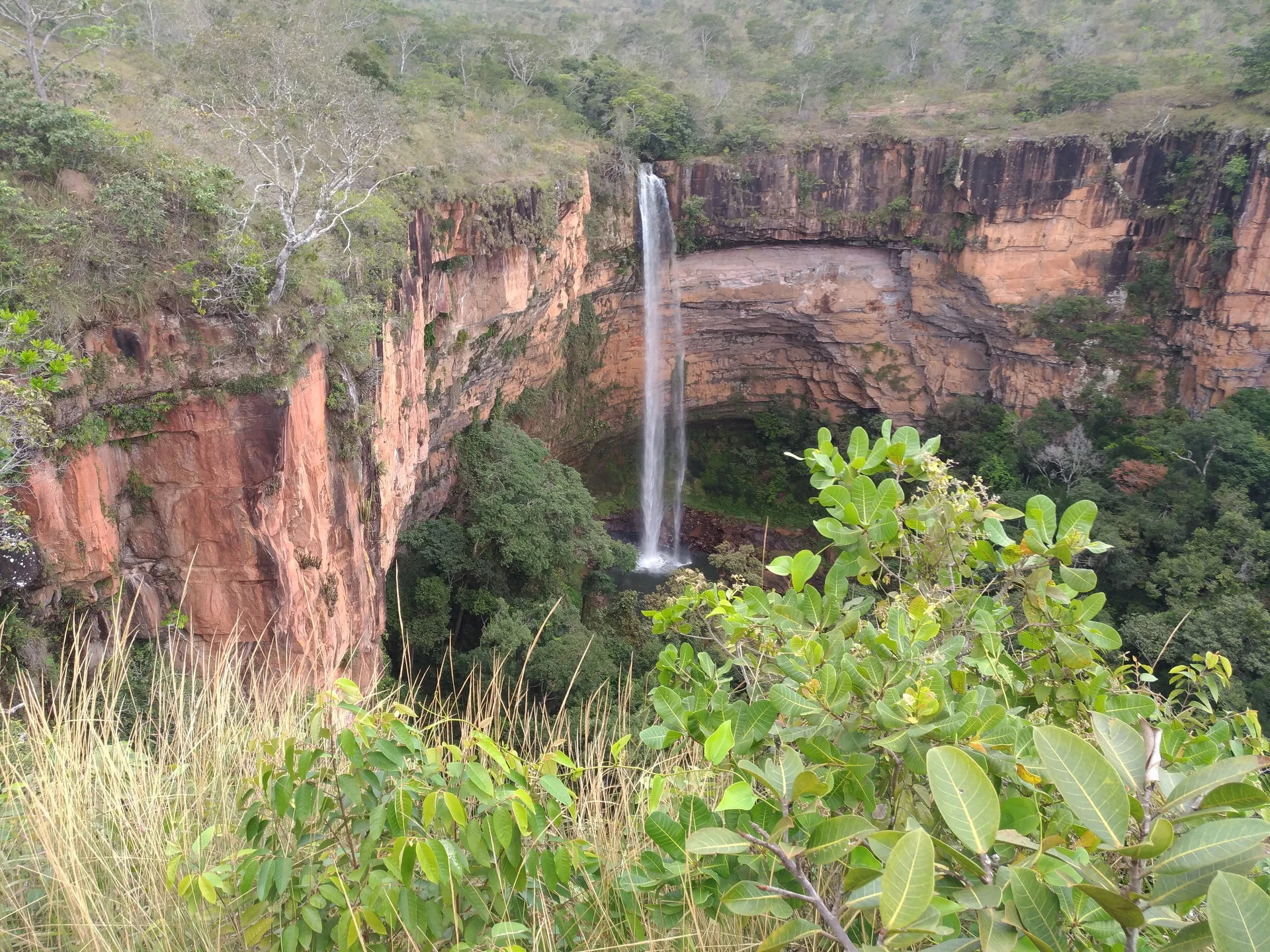 Cachoeira Véu de Noiva despencando entre paredões avermelhados e vegetação do Cerrado na Chapada dos Guimarães.