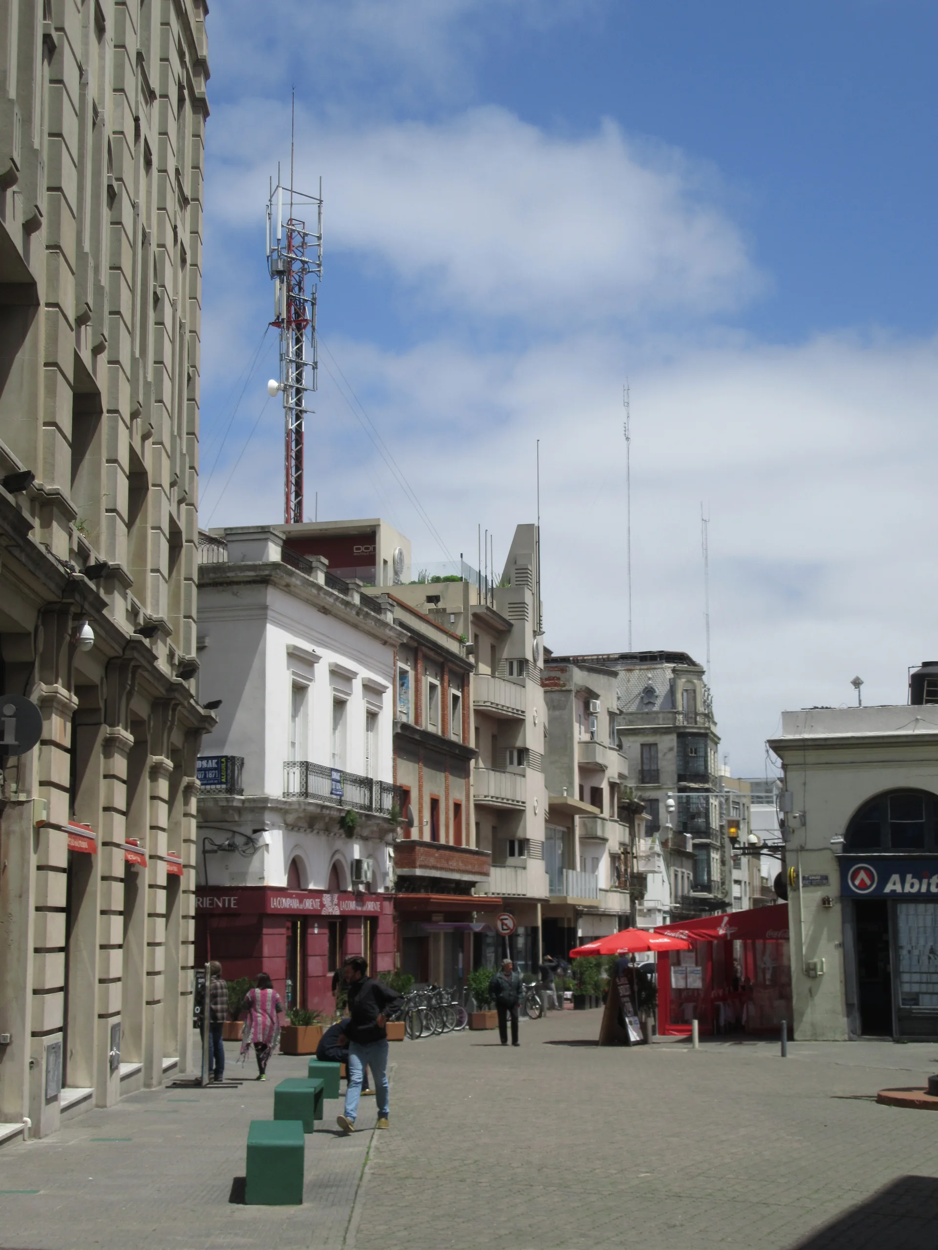 Trecho da Calle Piedras na Ciudad Vieja de Montevidéu, com fachadas históricas, comércio, bicicletas e pessoas na calçada.