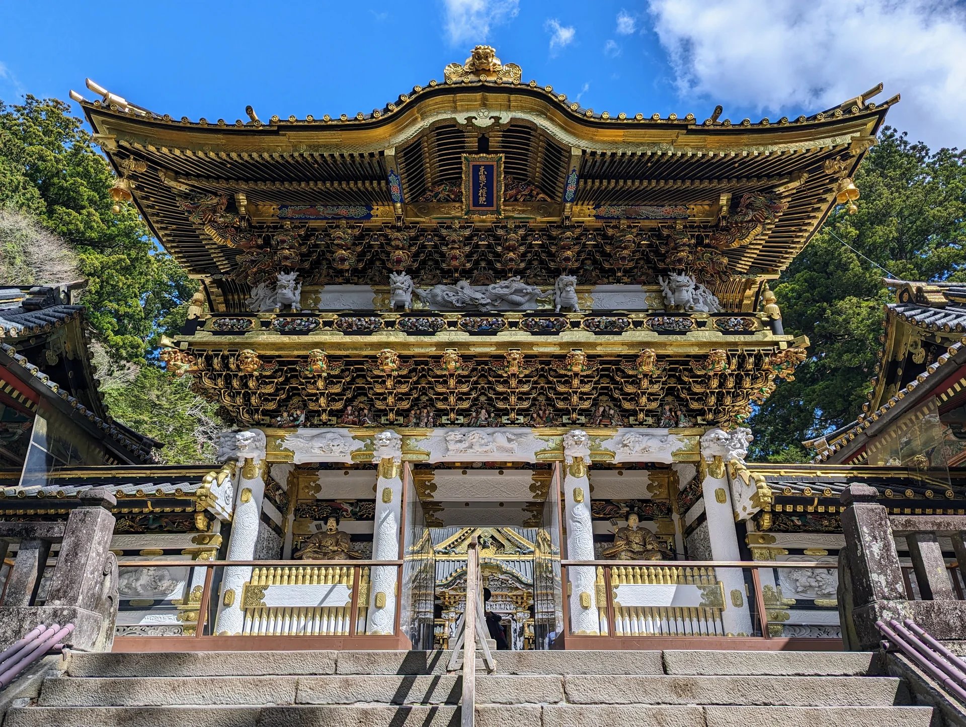 Portão Yomeimon do Santuário Toshogu em Nikko, com talha ornamentada, dourado e céu azul.