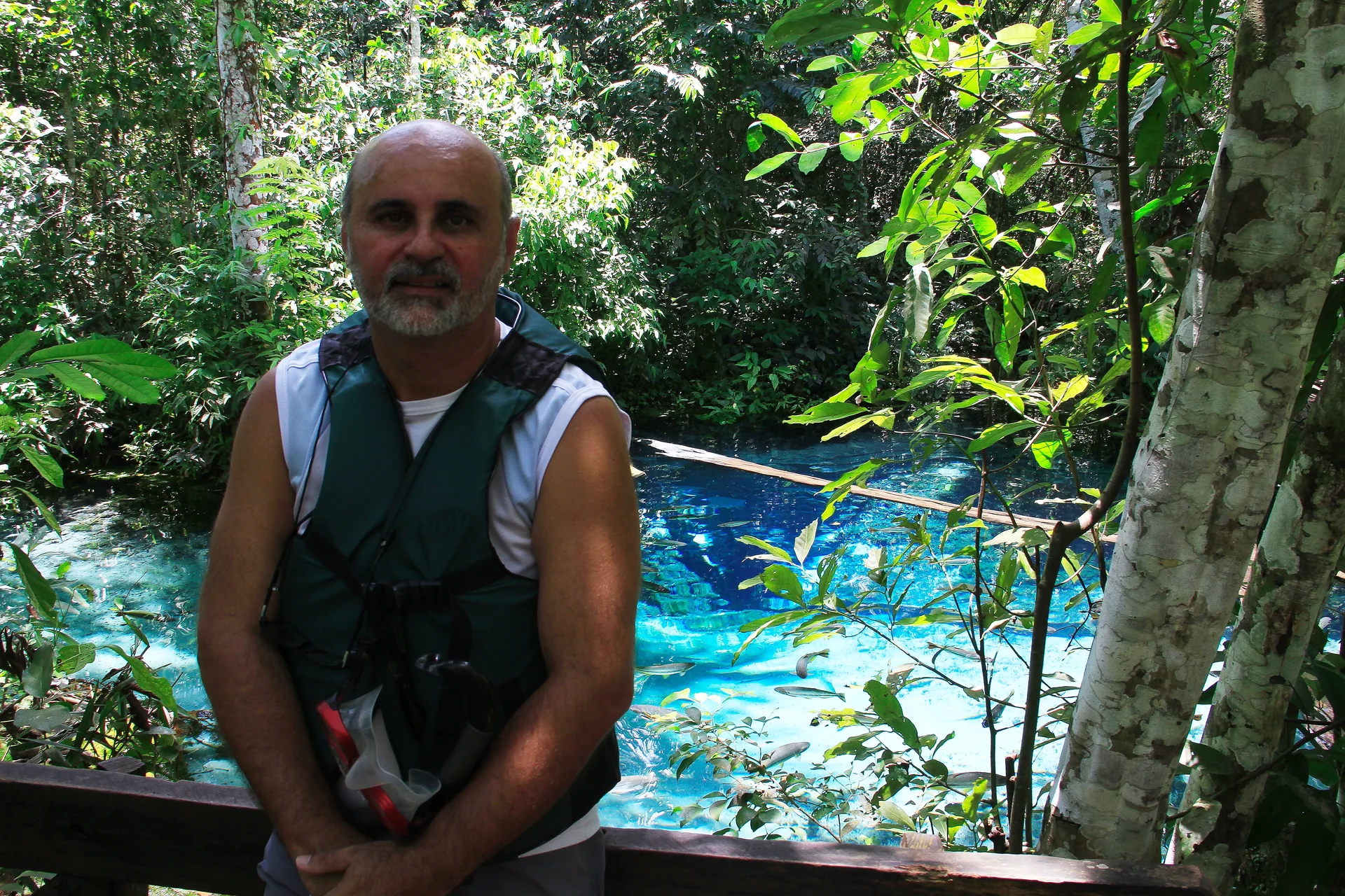 Visitante com colete e snorkel junto ao ponto de observação do Aquário Encantado, em Nobres, com a nascente ao fundo.