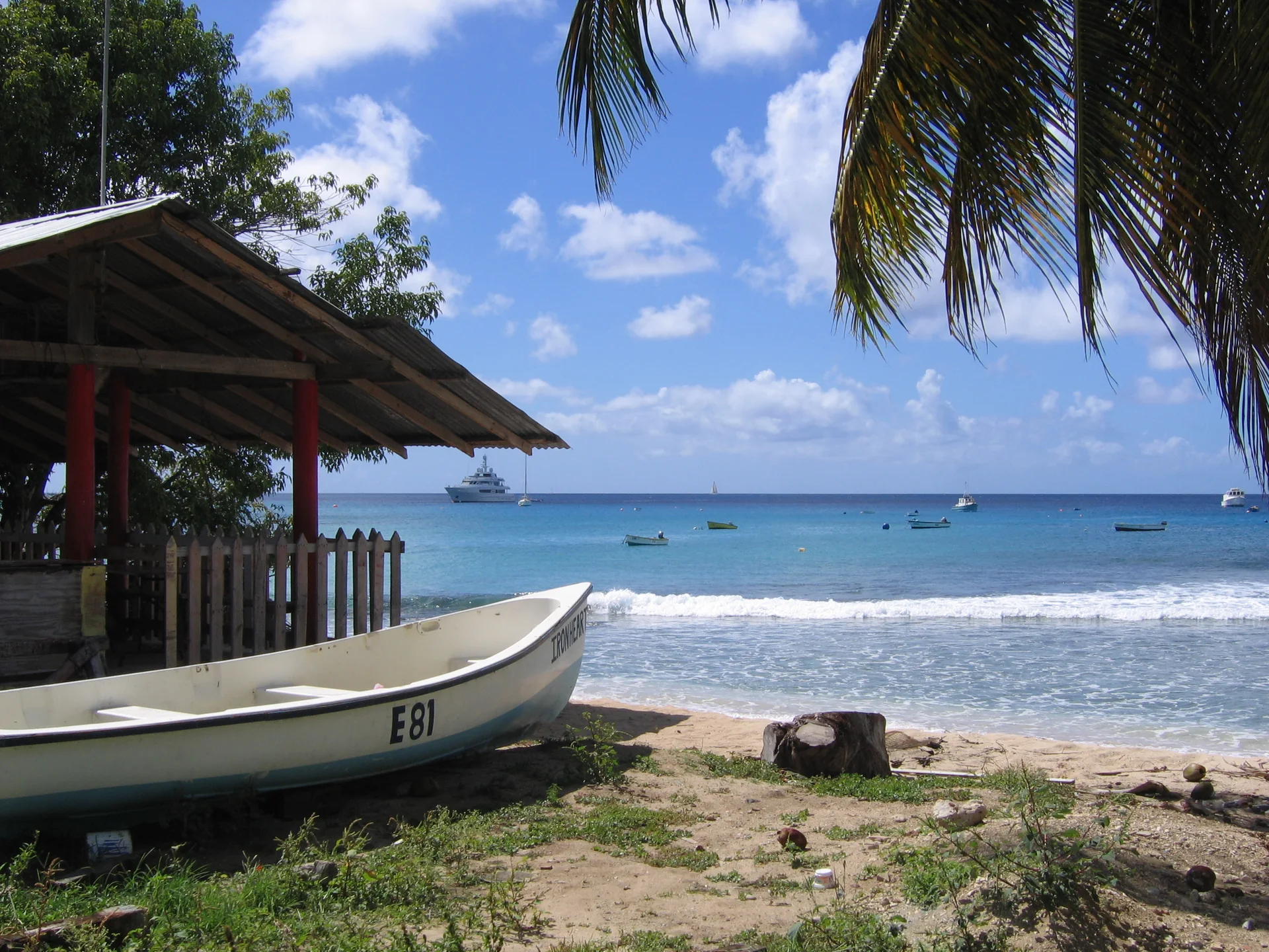 Barco de pesca junto à areia e pequenas embarcações no mar da costa oeste de Saint Peter, Barbados.