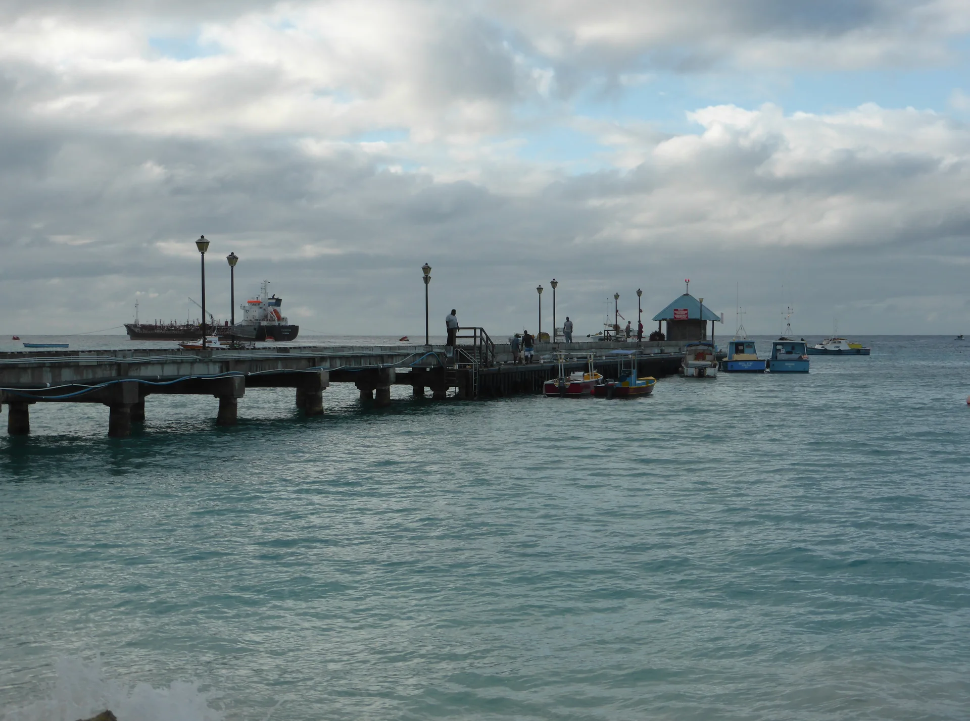 Cais do Porto de Oistins com pequenas embarcações e mar sob céu nublado em Barbados.