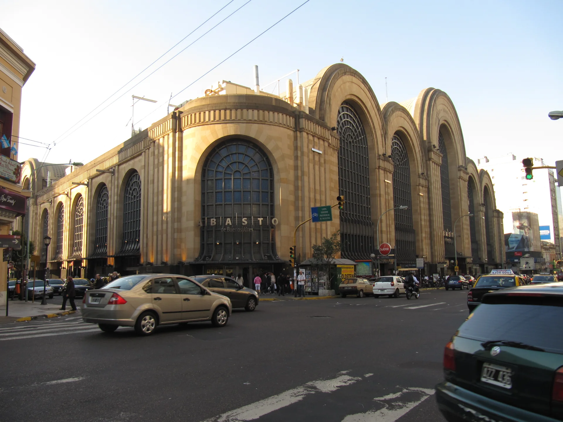 Fachada art déco do Shopping Abasto em Buenos Aires, vista de esquina durante o dia, com arcos altos e o letreiro Abasto.