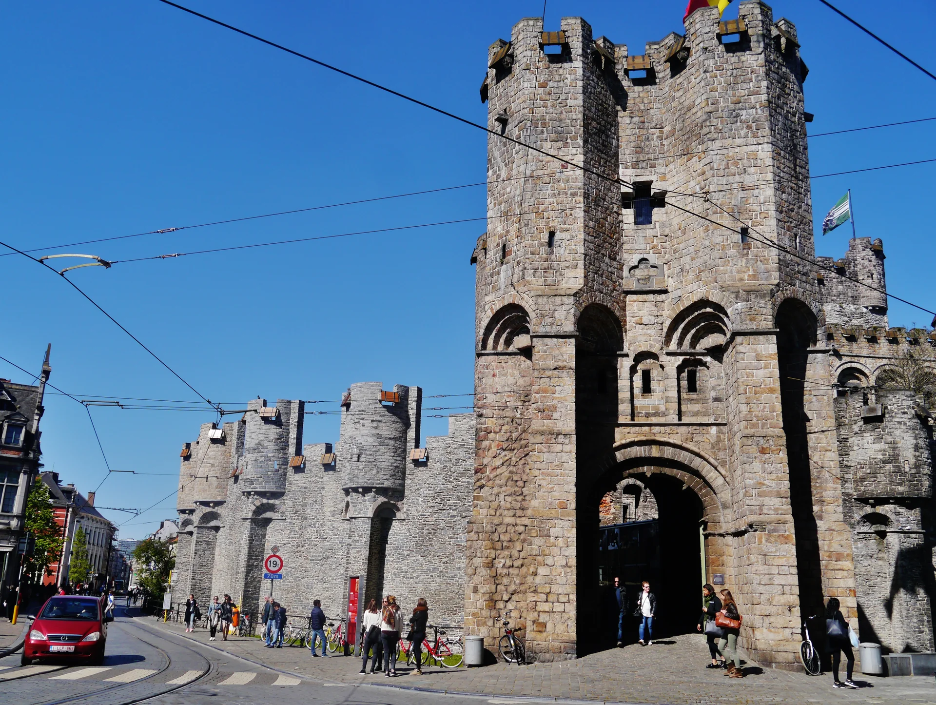 Entrada fortificada do Castelo Gravensteen, com portão em arco e torre de pedra em luz natural.